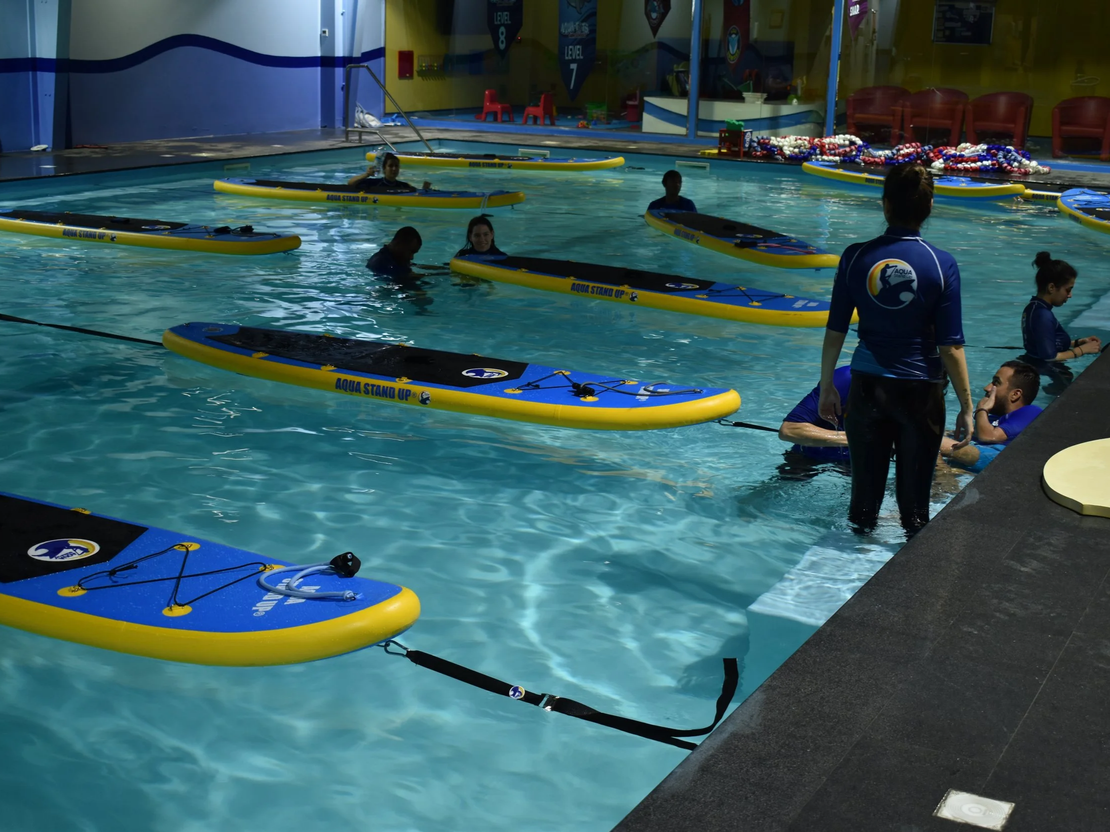 AQUA STAND UP® boards set up in a swimming pool with aquastandup instructors