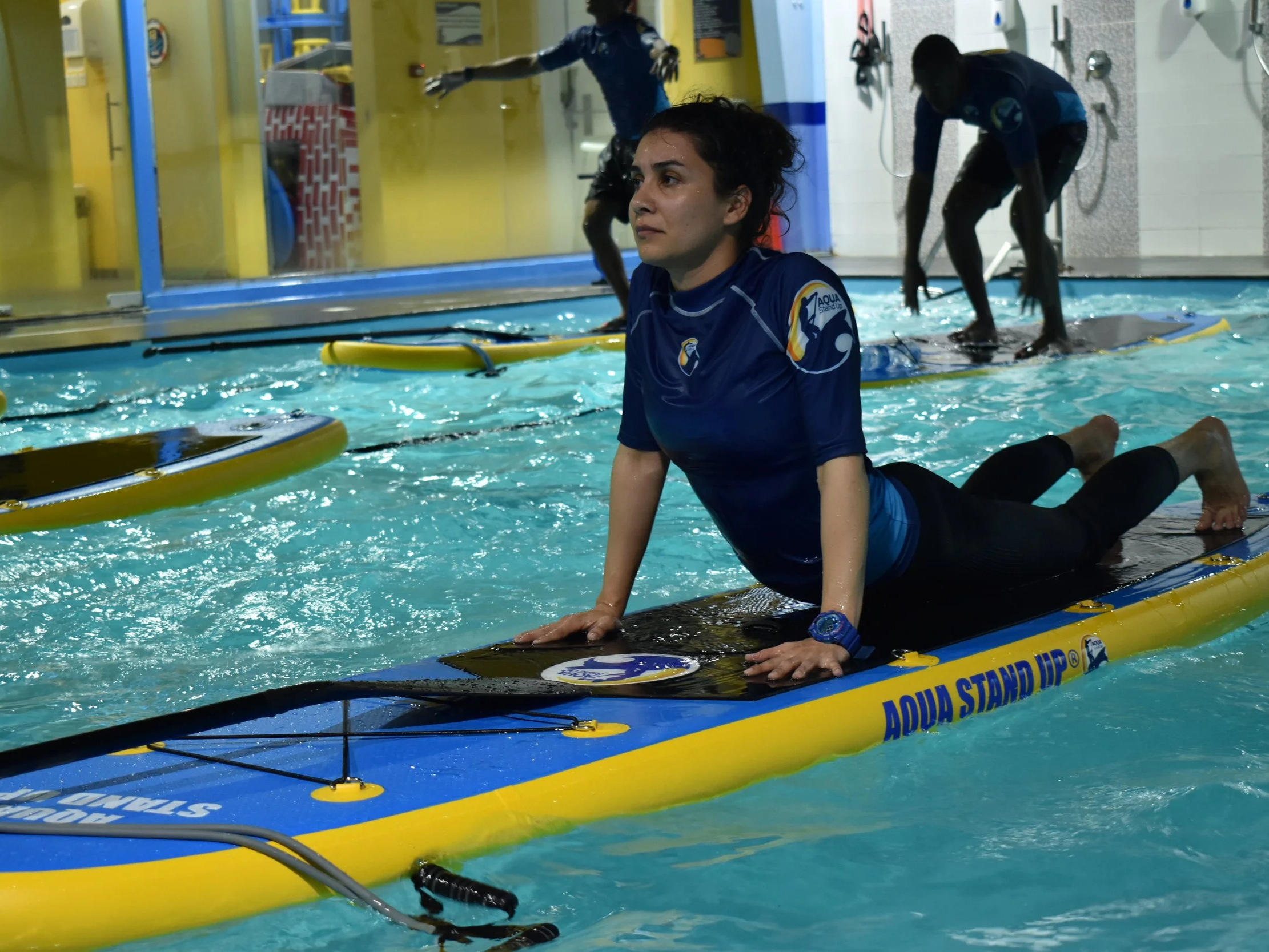 AQUA STAND UP® instructor into up dog pose on an aquastandup board in a swimming pool