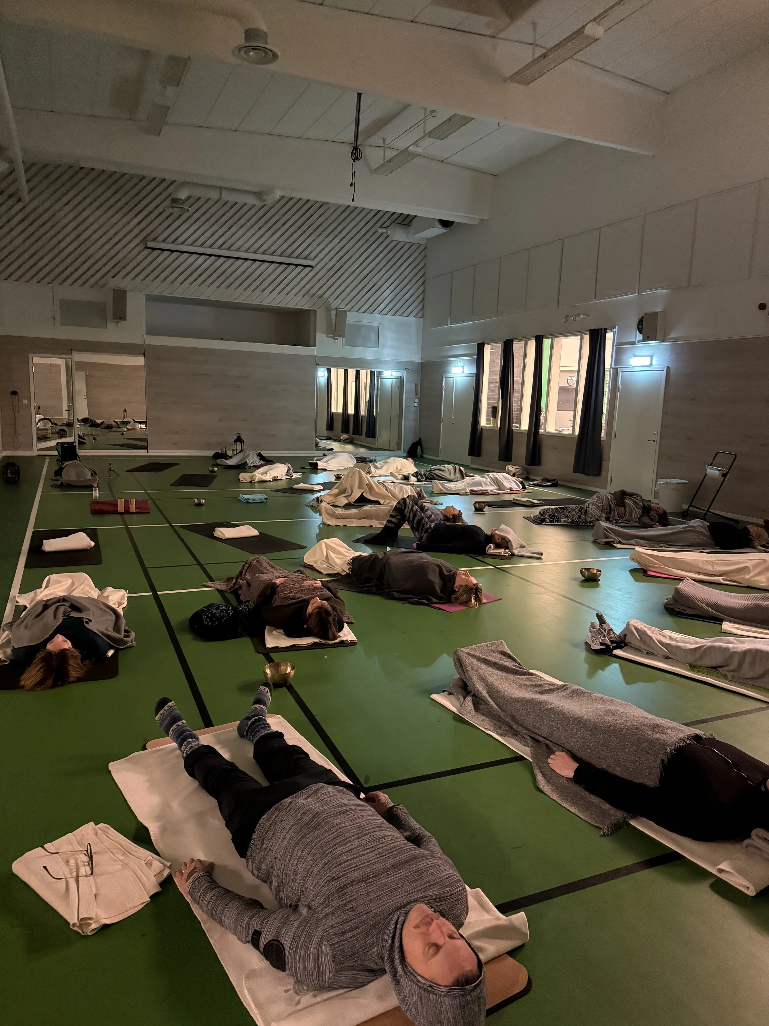 Människor som vilar på mattor i ett inomhusrum, deltagare i en breathwork klass.