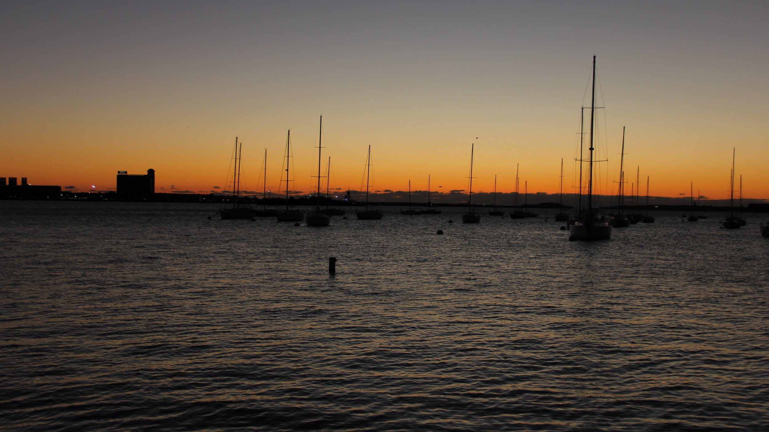 The sun sets over the Charles River as boats come back to dock for the night.