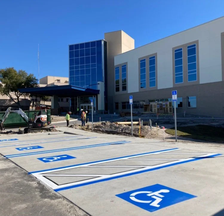 Newly painted handicapped parking spaces in front of a building under construction.