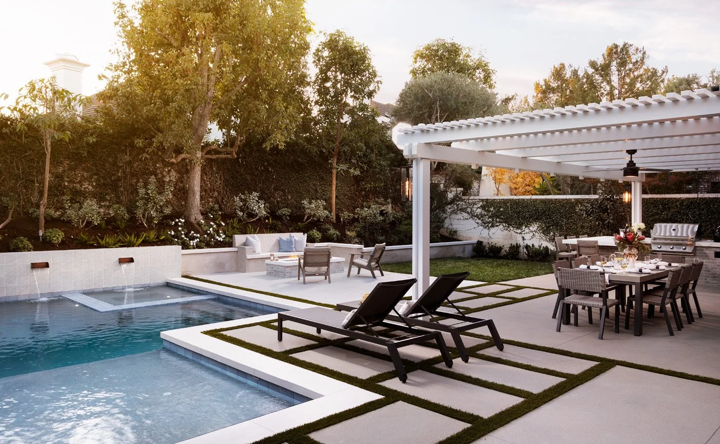 Backyard patio with a swimming pool, lounge chairs, an outdoor dining table with chairs, a pergola, and a garden with trees and shrubbery.