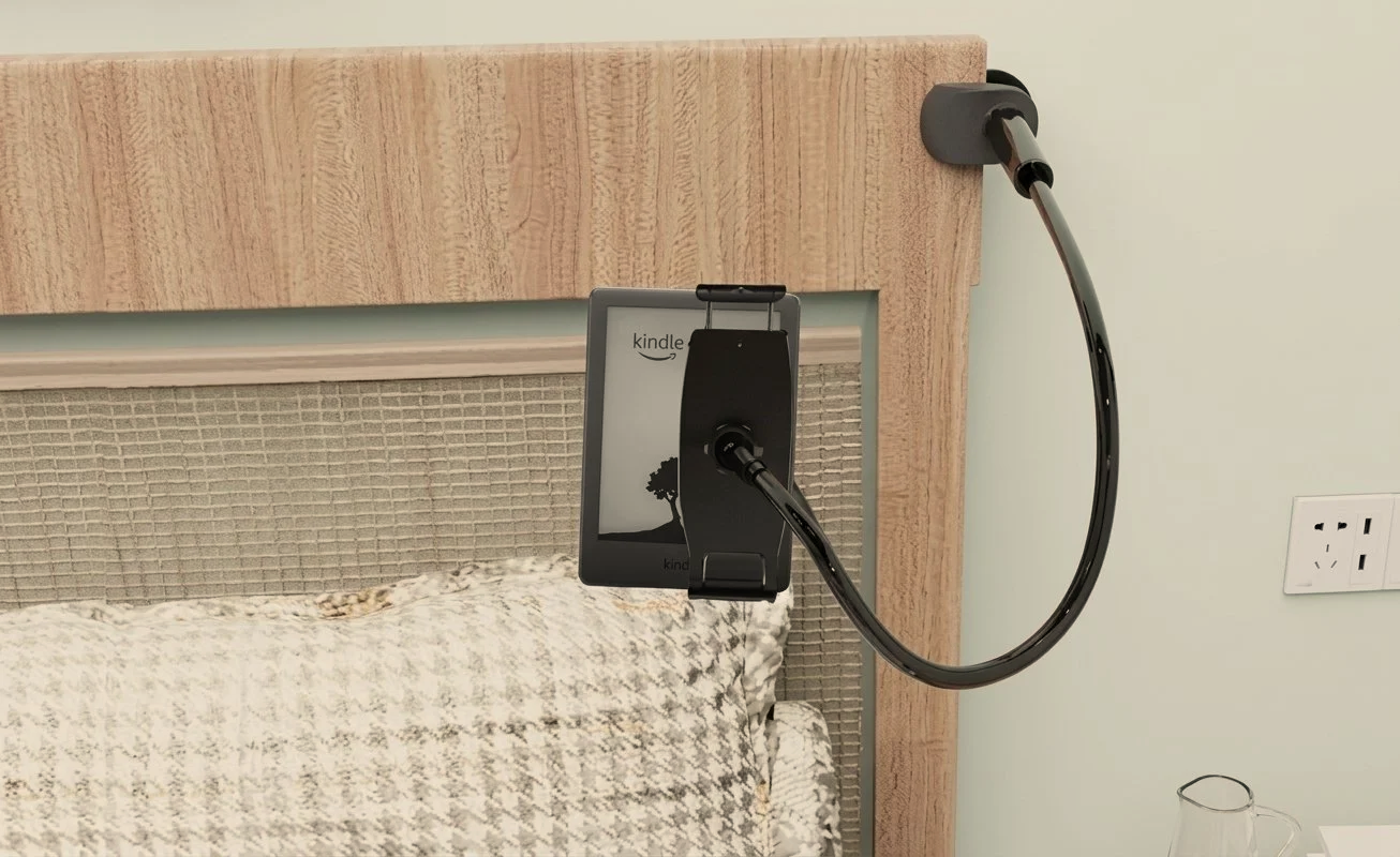 A phone mounted on a wooden headboard with a black cable connected to it, positioned above a bed with a patterned blanket.