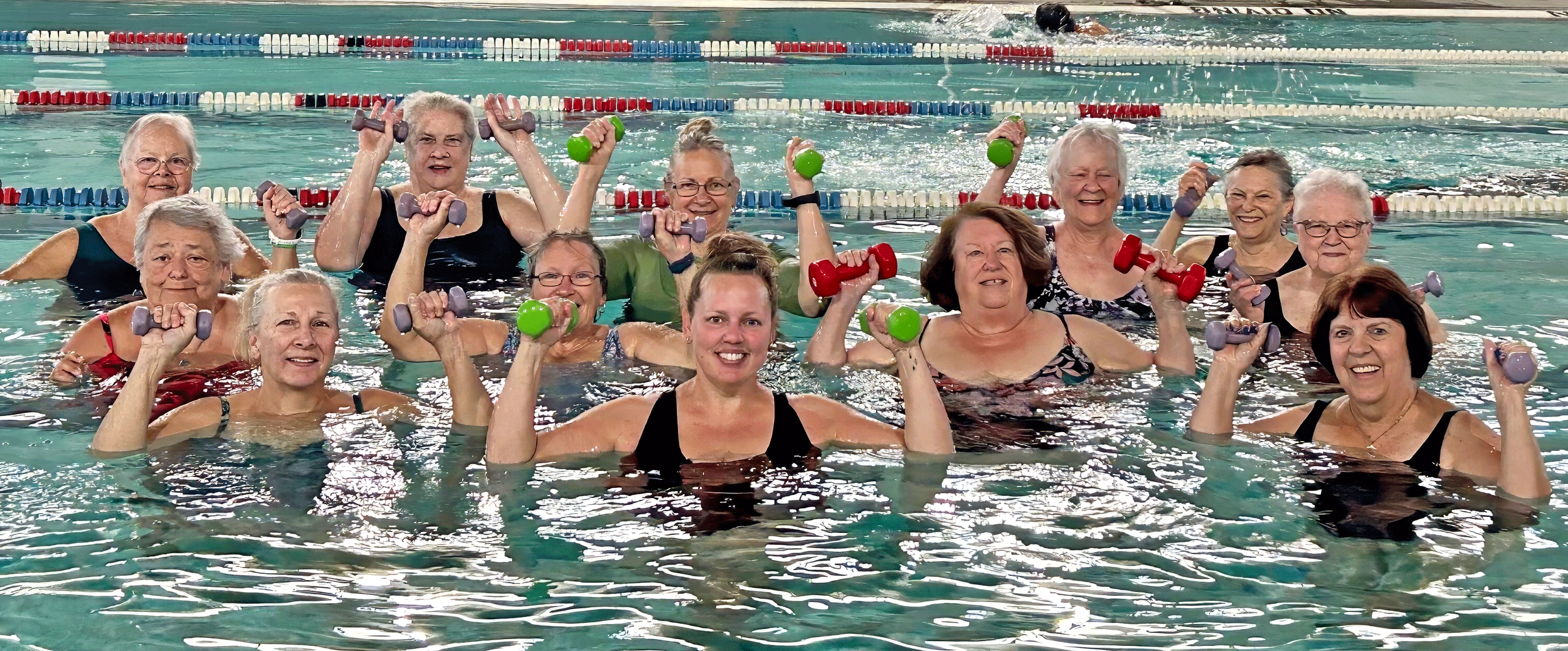 Aqua Fitness members smiling in the YWCA pool with hand weights.