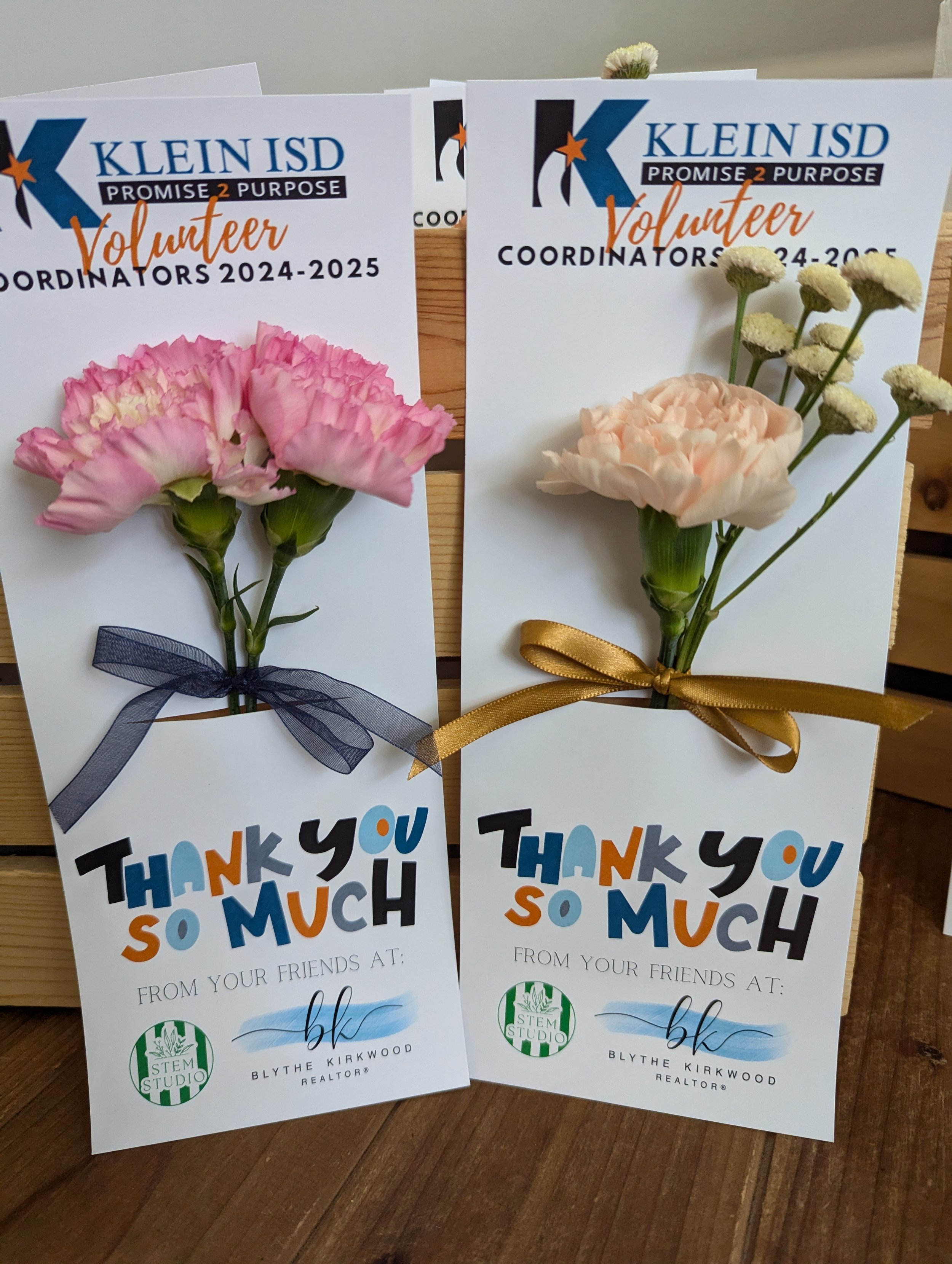 Thank you cards from a school district, each decorated with a flower and tied with a ribbon—one pink with a navy ribbon, one peach with a gold ribbon.