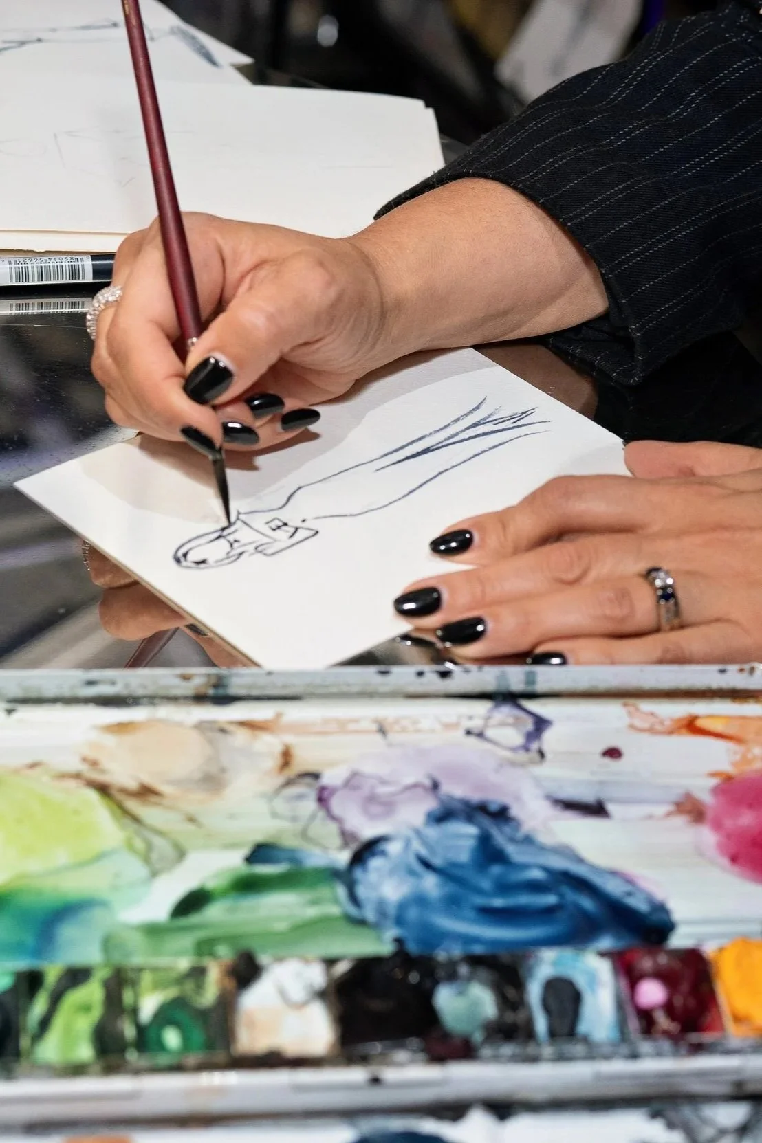 Zoomed in picture of hands with black manicured nailspainting a fashion portrait