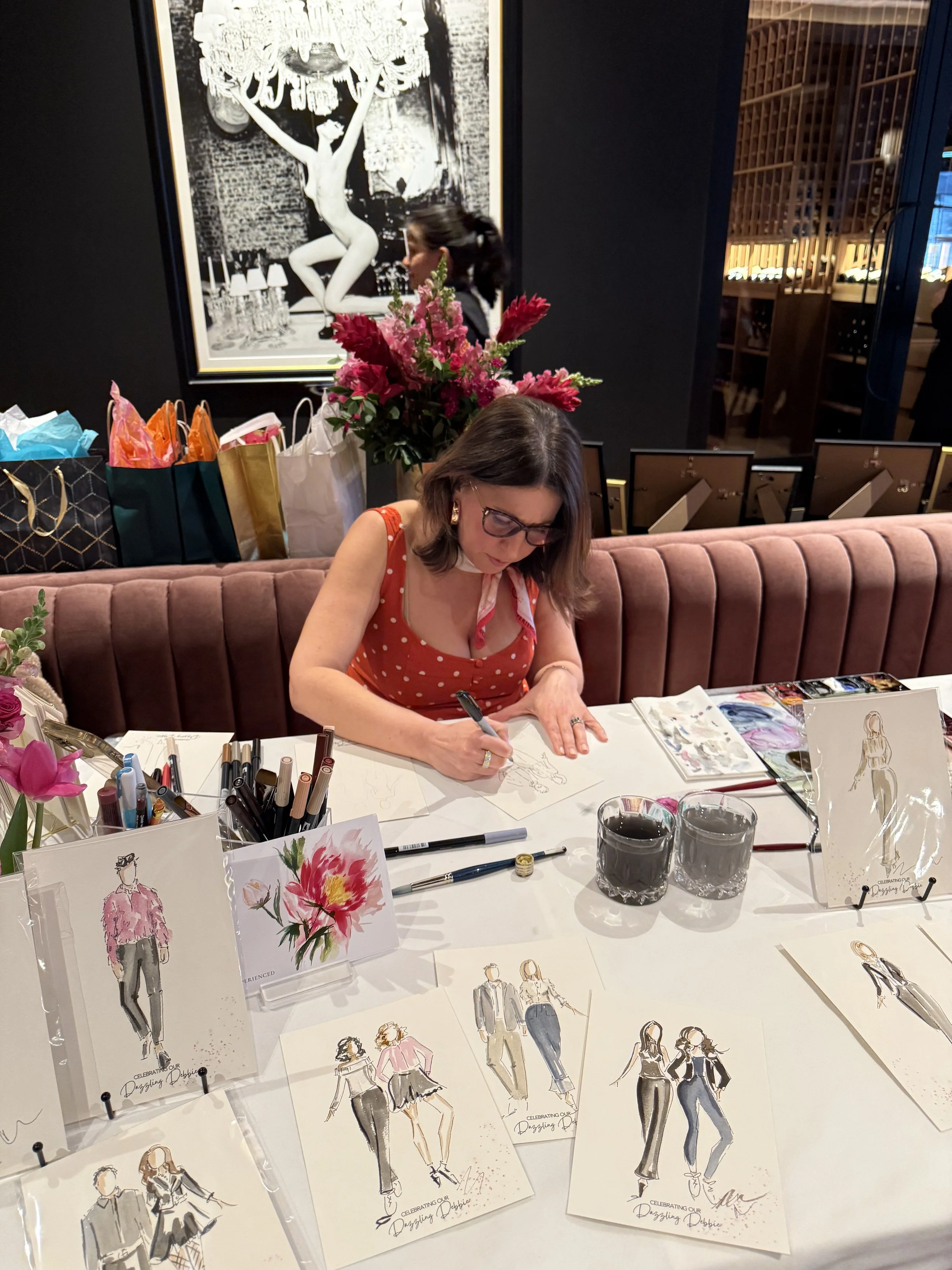 woman painting guest portraits at an event while wearing a red polka dot dress