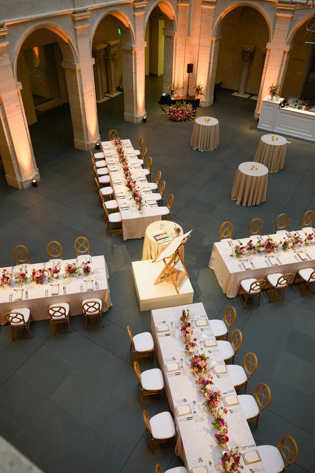 a zoomed out photo of an event set up where 4 long tables form an X shape