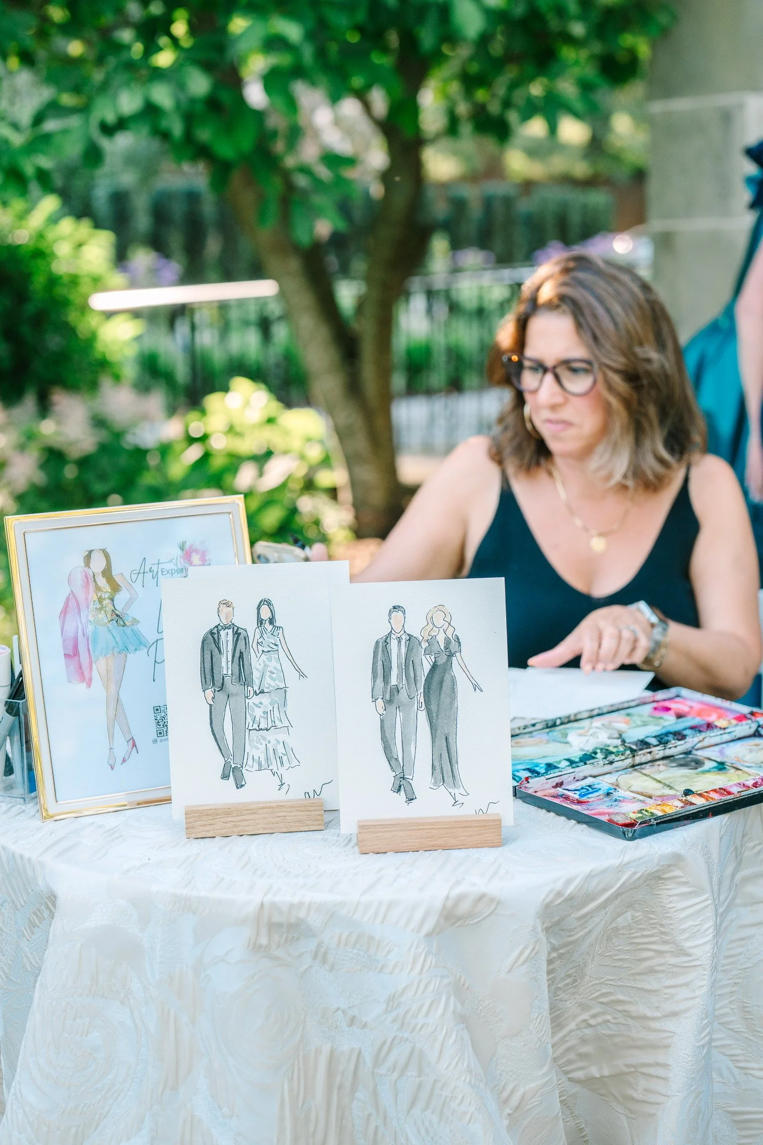 Artist in black sits and paints event guests