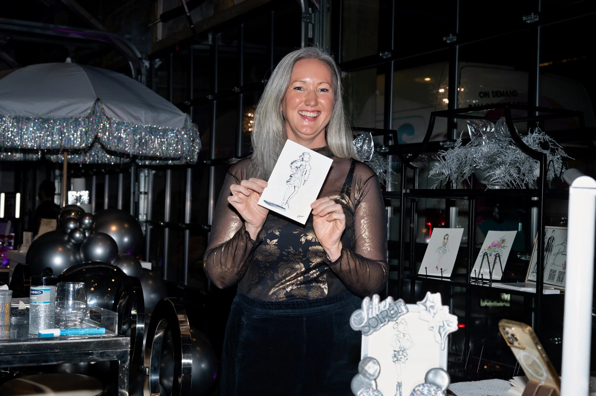 Smiling silver-haired Woman holding a fashion portrait drawn of her