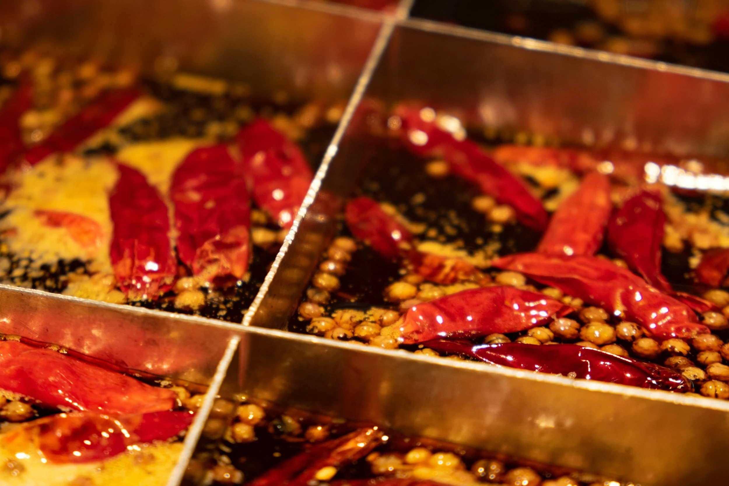 Close-up view of red chili peppers and sesame seeds in a cooking pan, with a divider separating sections.