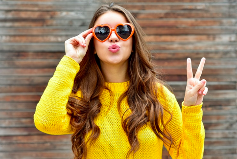 Woman with long hair and sunglasses making a peace sign, about an article for hair care