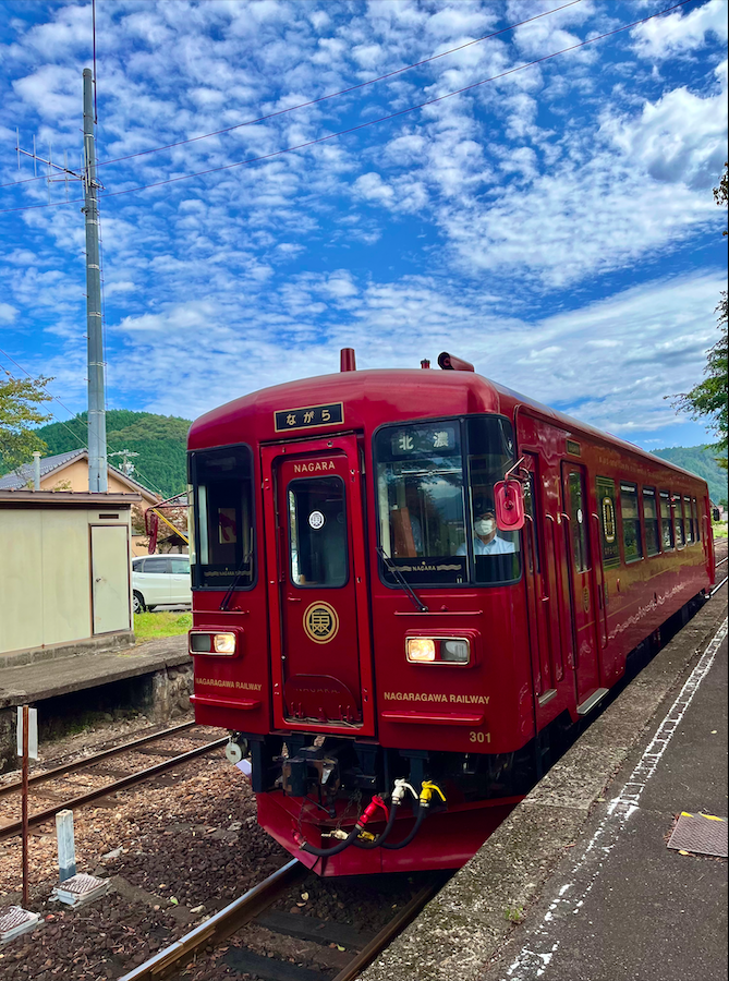 A vintage, red, single-car train that takes you along one of the most scenic train routes in Japan, along the Nagara River.