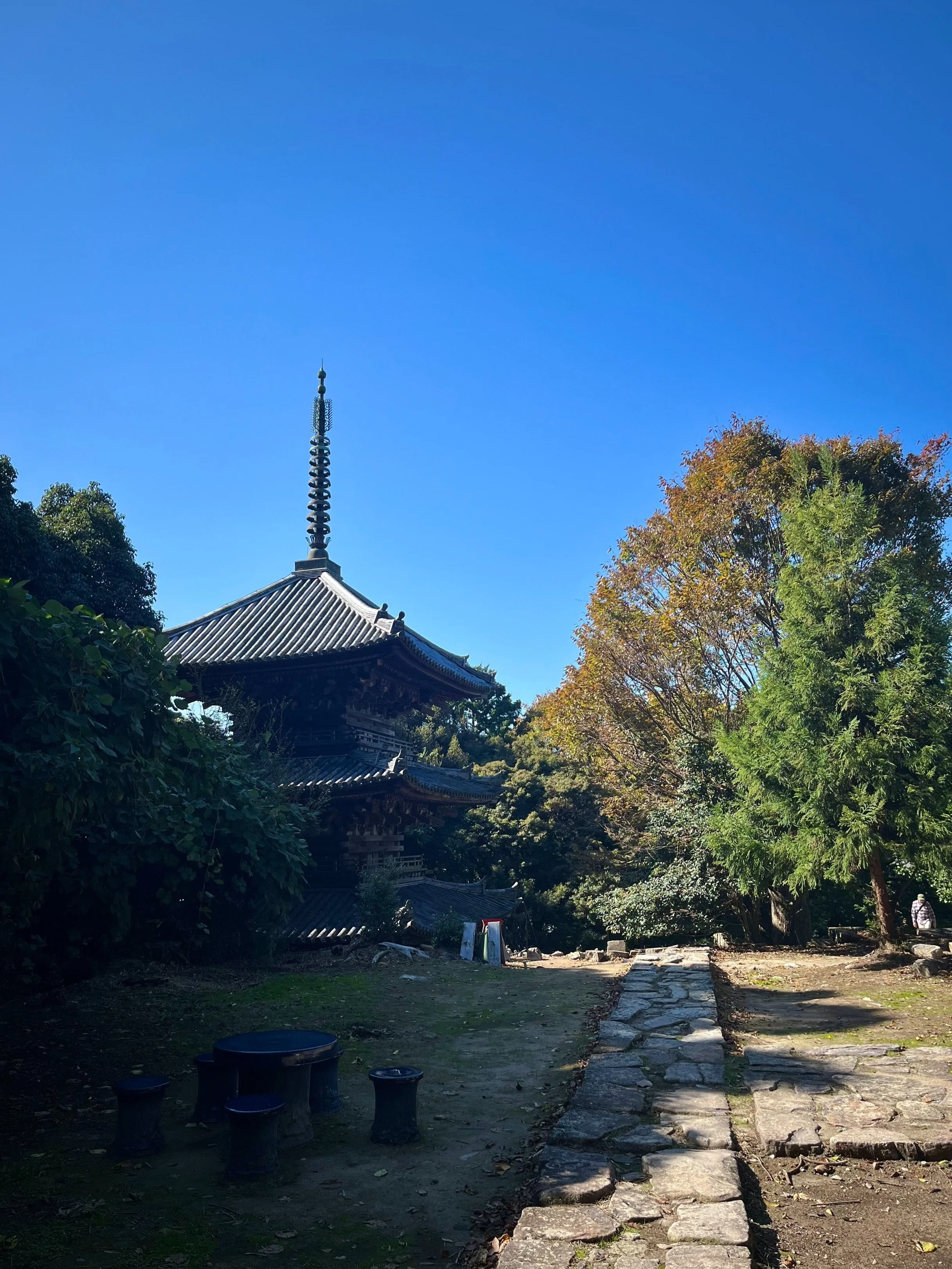 A pagoda with a stone path leading to it under a clear blue sky