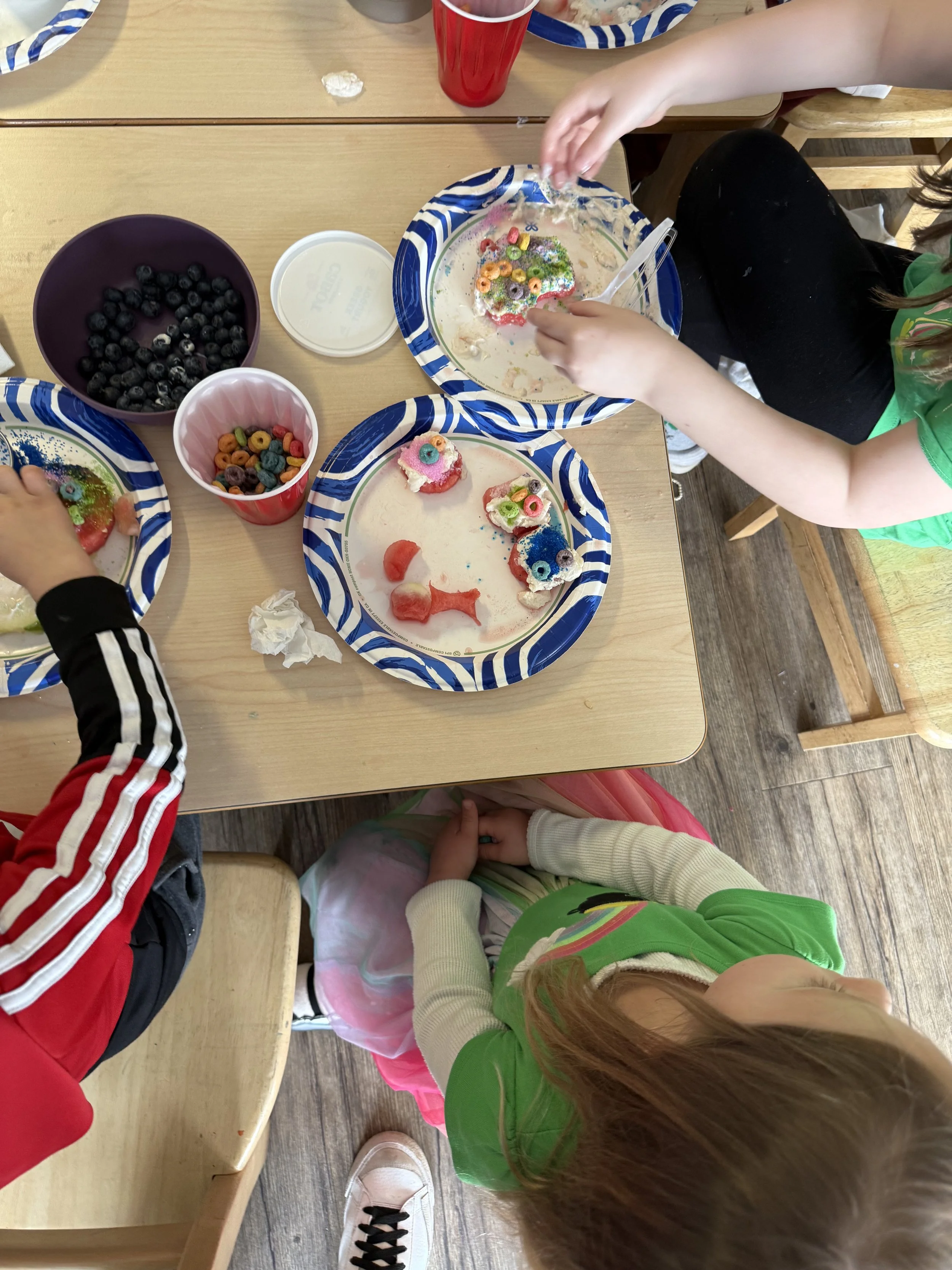 Children in a classroom wearing aprons preparing food at a counter