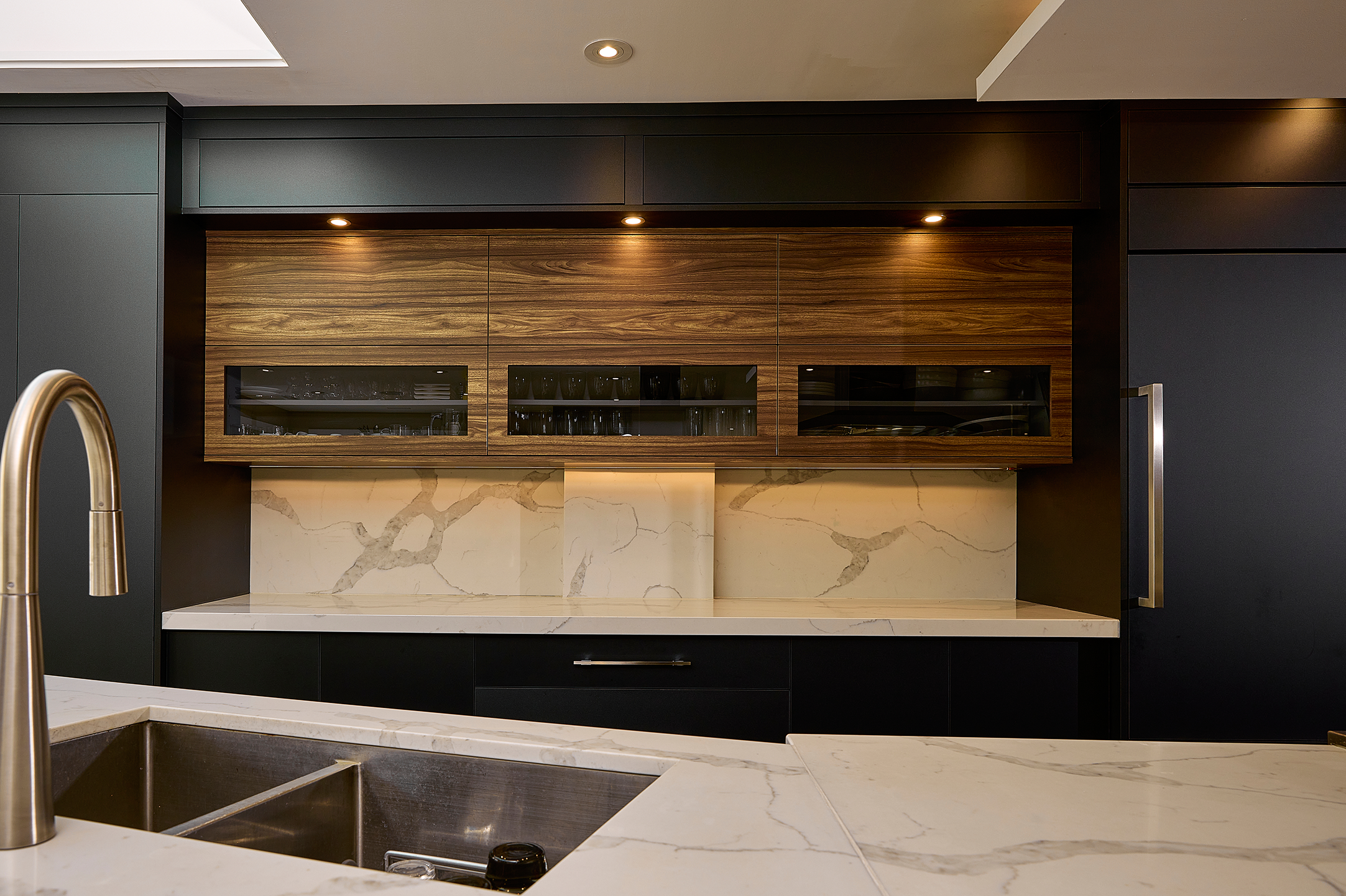 Modern kitchen with marble countertops, dual stainless steel sink, wooden cabinets, and recessed lighting.
