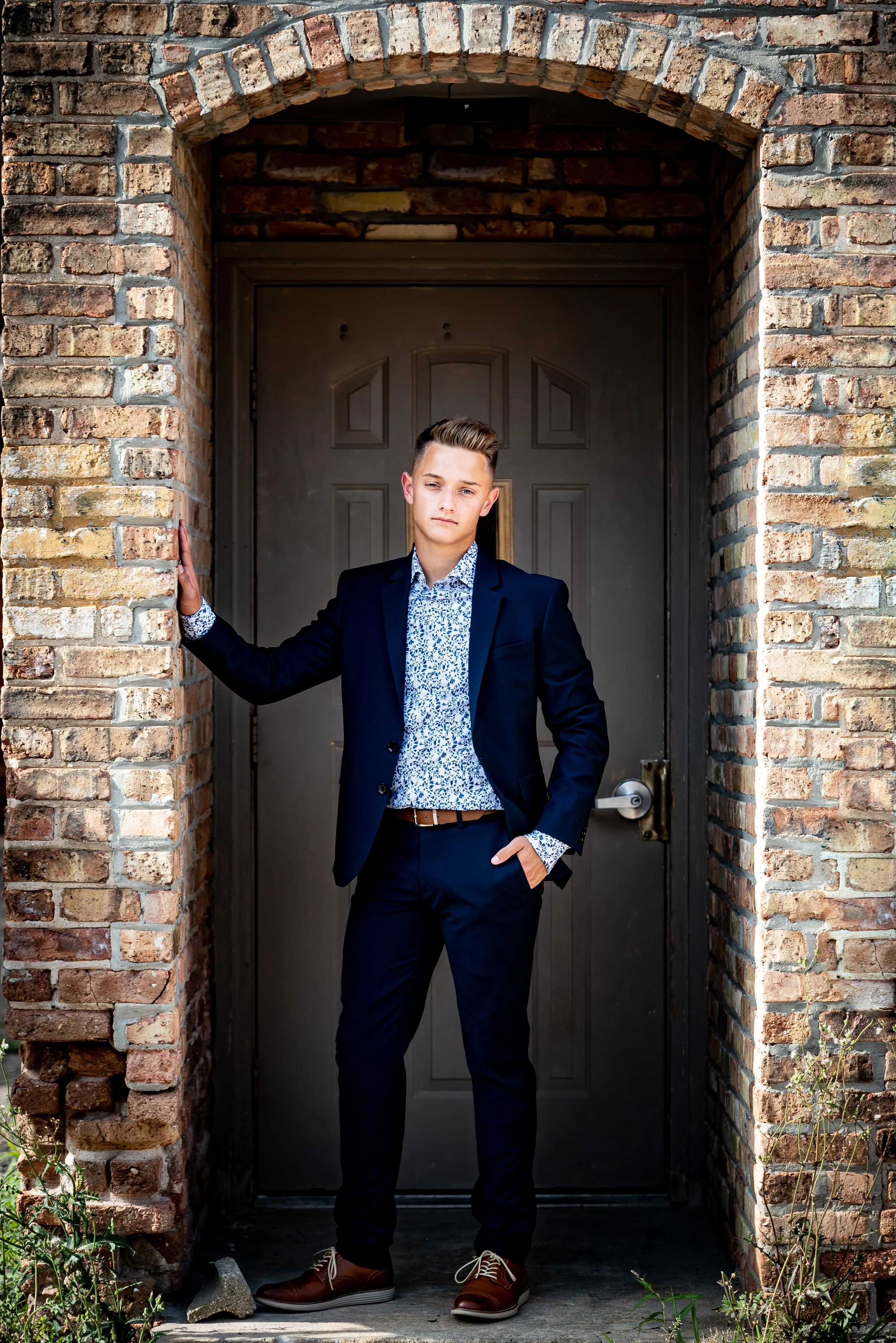 Young man in a suit standing in a brick archway for formal senior portraits in Baraboo, WI.