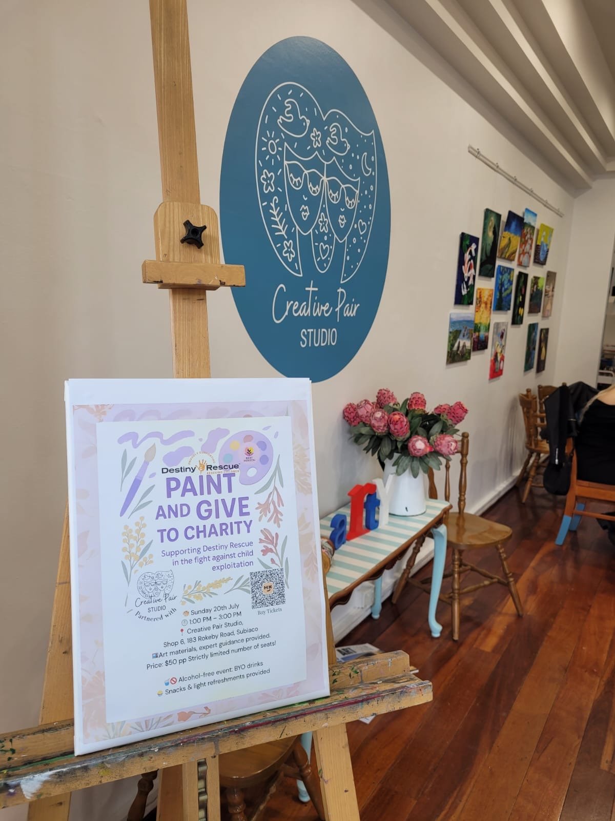 Sign promoting charity event for Destiny Rescue, about painting and giving to charity, supporting against child exploitation, scheduled for Sunday, July 20th, 1 PM to 3 PM at Creative Pair Studio. The studio has art supplies and is located at 183 Rokeby Road, Subiaco. The event features an alcohol-free environment, snacks, and light refreshments.