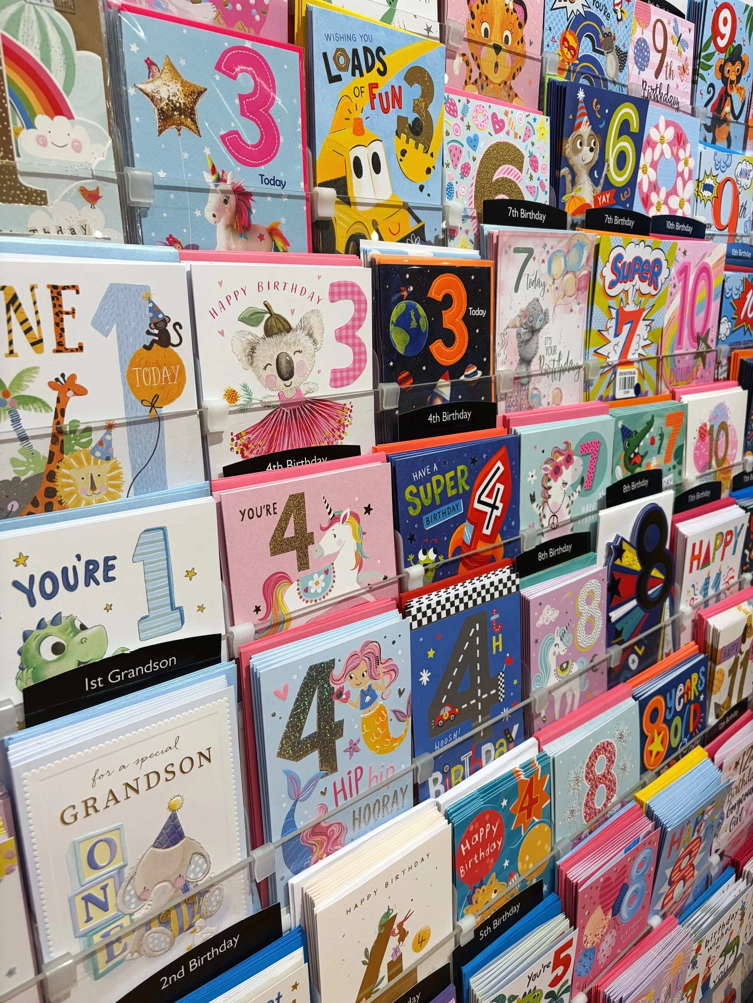 A display of colorful birthday greeting cards for children, featuring animals, numbers, and playful designs.