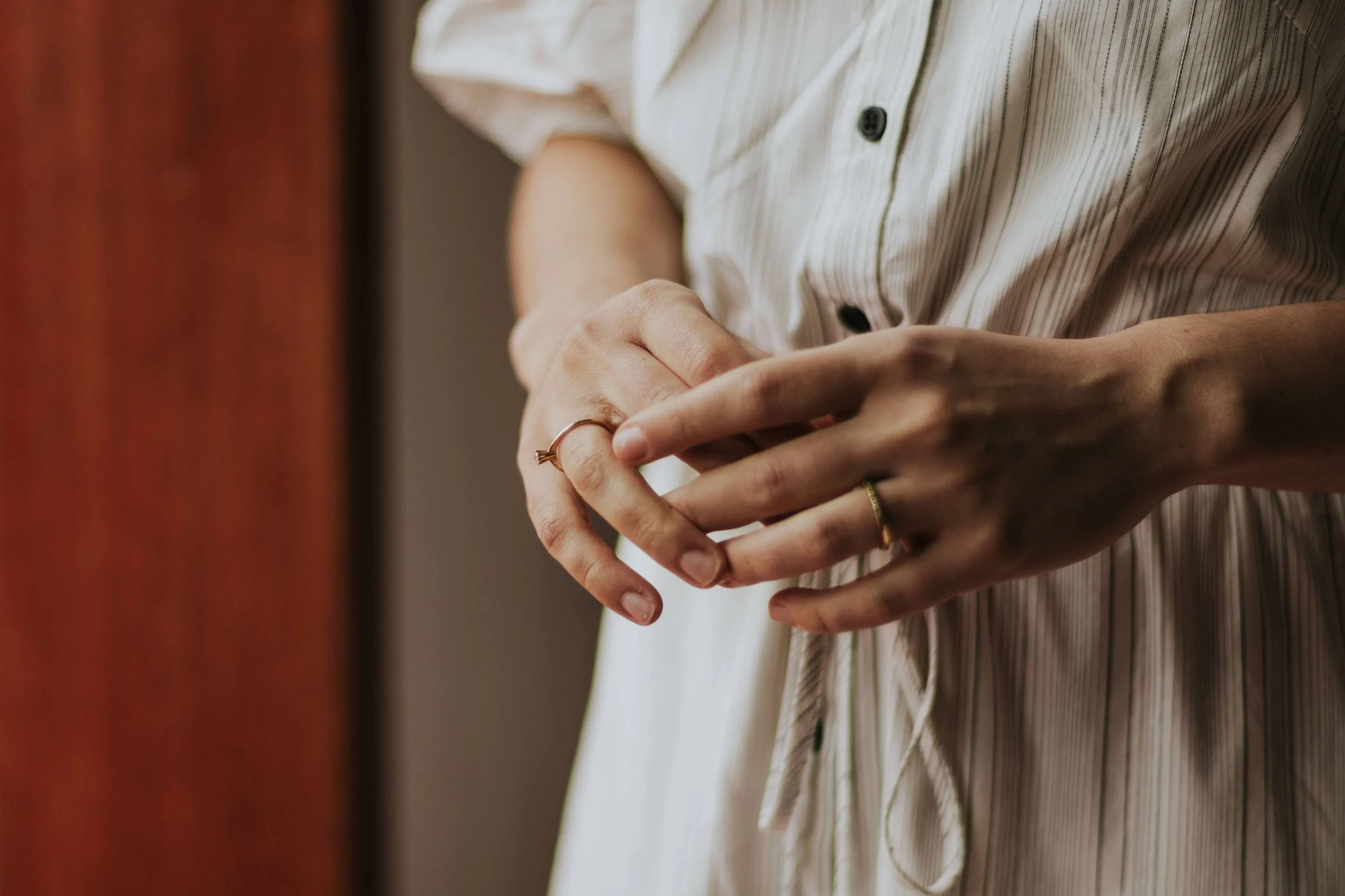 A woman's hands resting quietly in her lap, a moment of calm in soft light