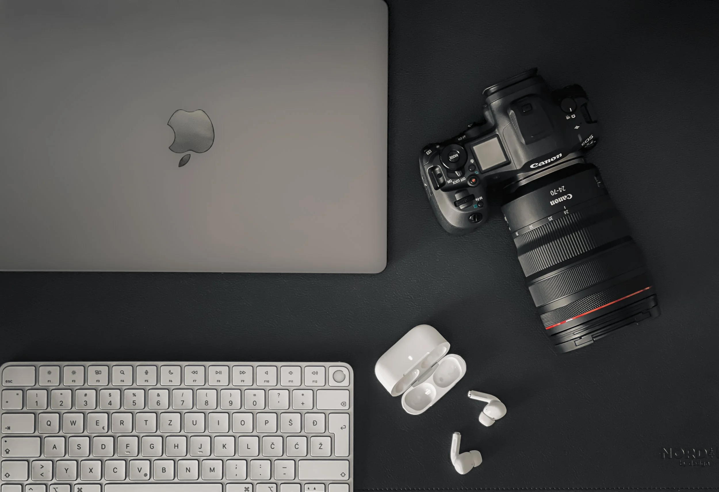 Cinematic flatlay of camera gear and MacBook for brand photography and digital marketing.