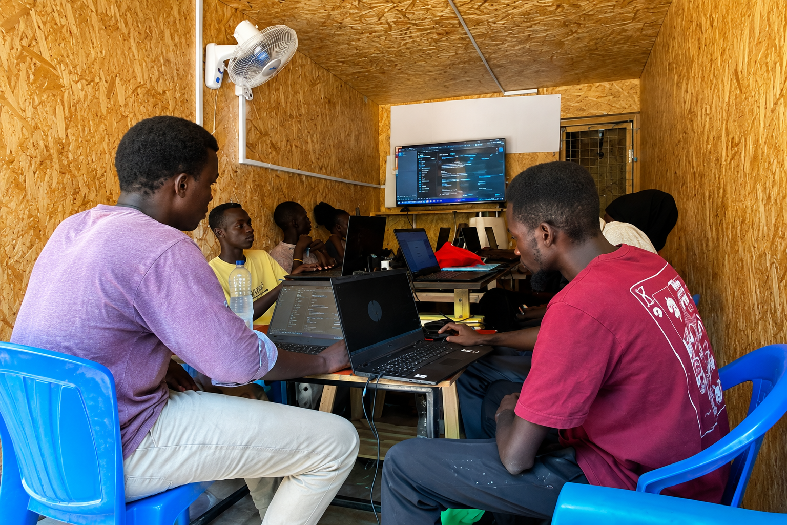 Young people using laptops during a Creative Gateway digital skills training session inside the Creative Hub in Kakuma Refugee Camp, Kenya.
