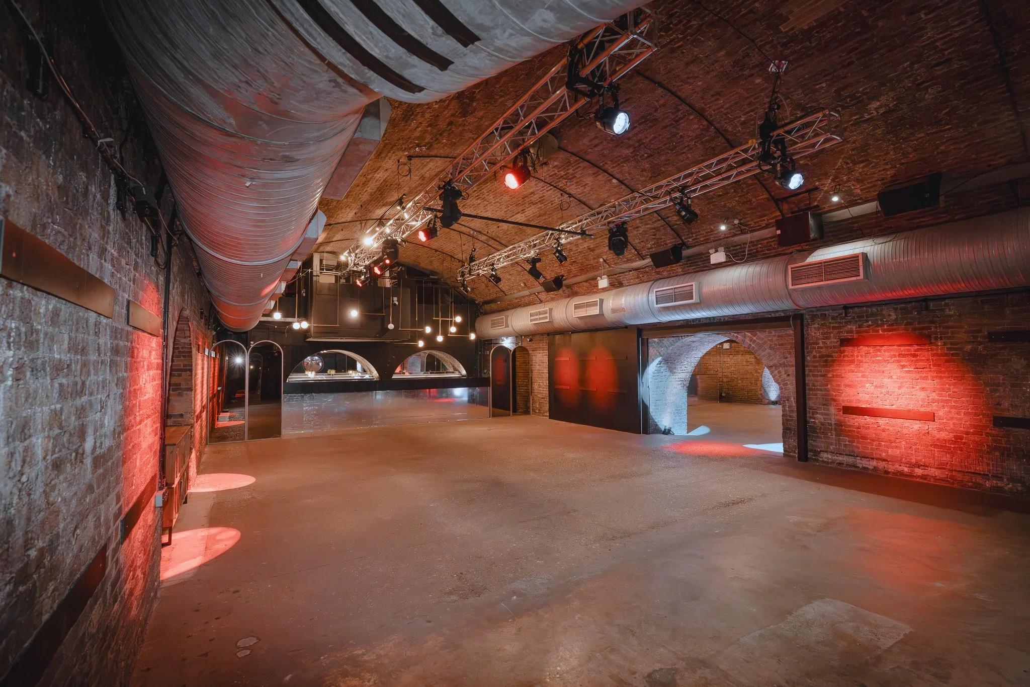Railway arch event space with red uplighting and lighting rig