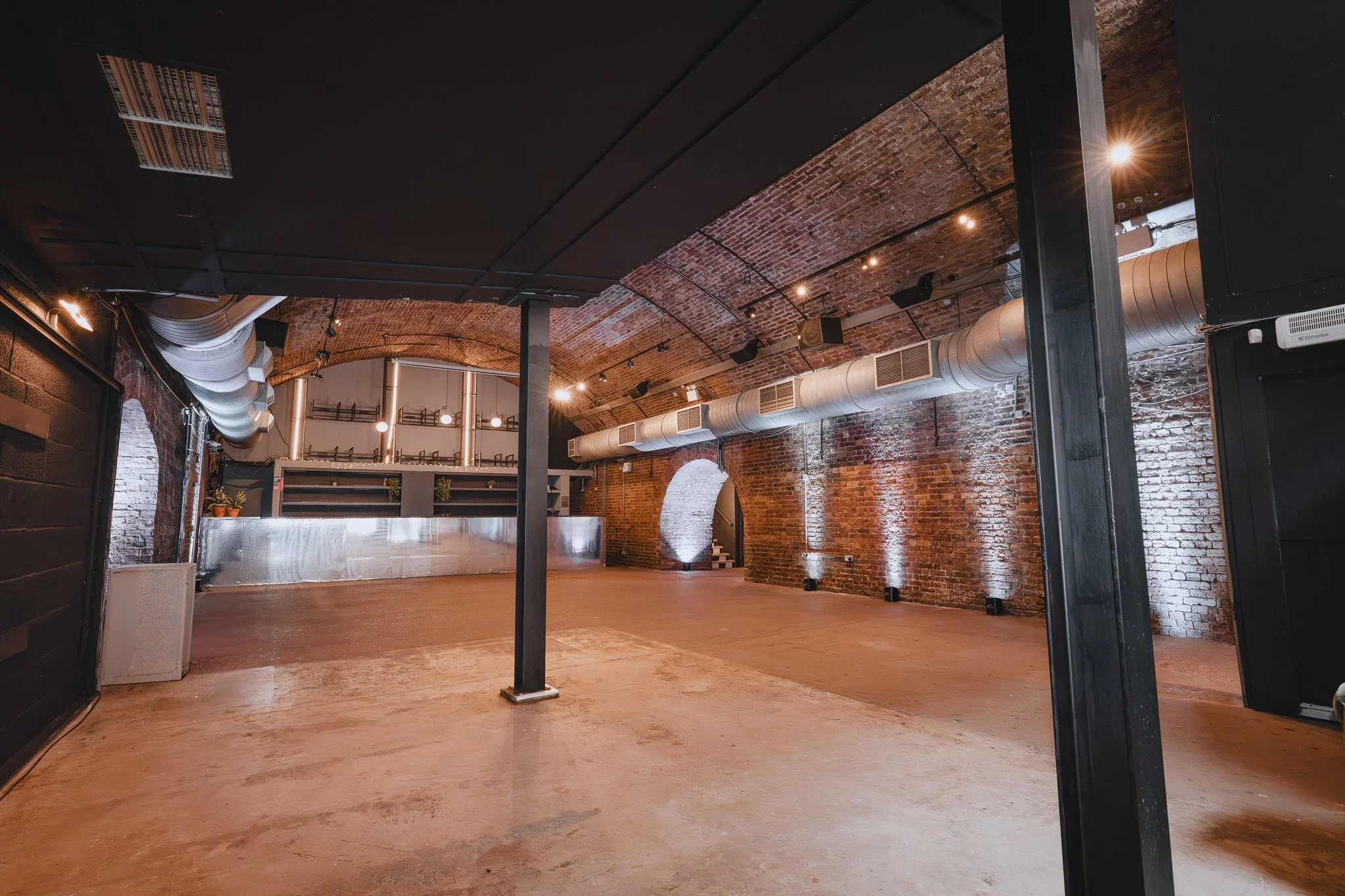Open-plan railway arch event space with bar and vaulted brick ceiling