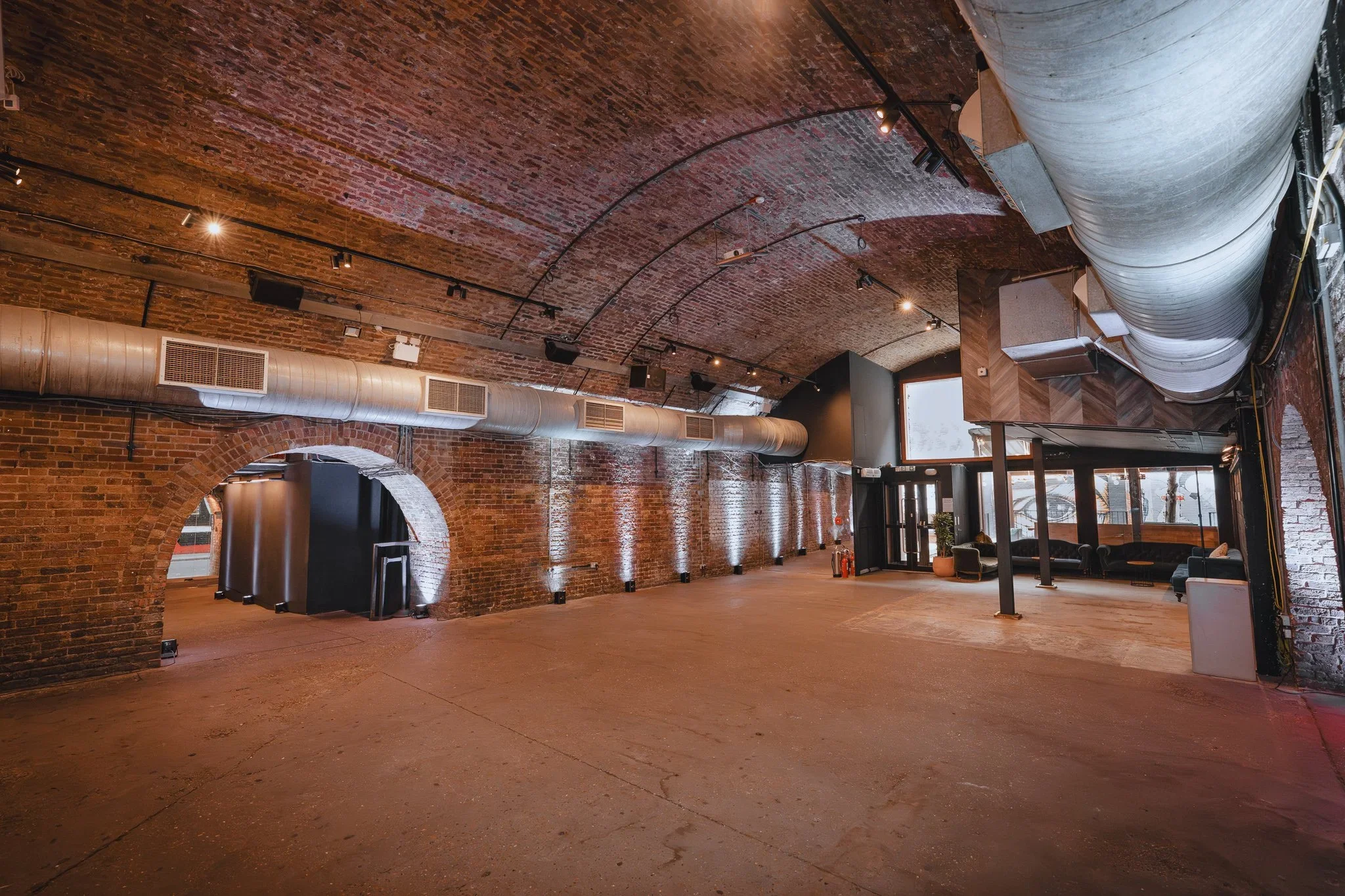 Railway arch event space with uplit brick walls and arched openings