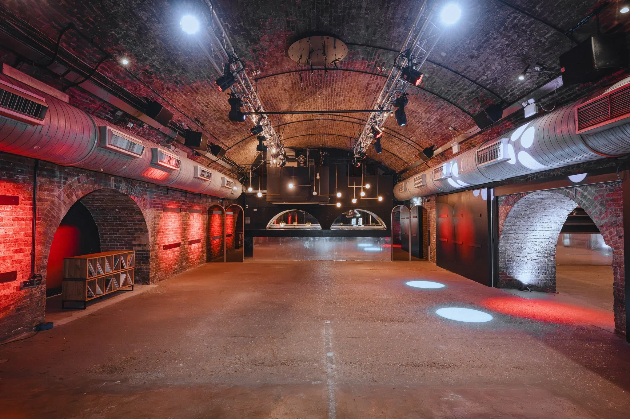 Long railway arch venue space with red lighting and exposed brick, Shoreditch