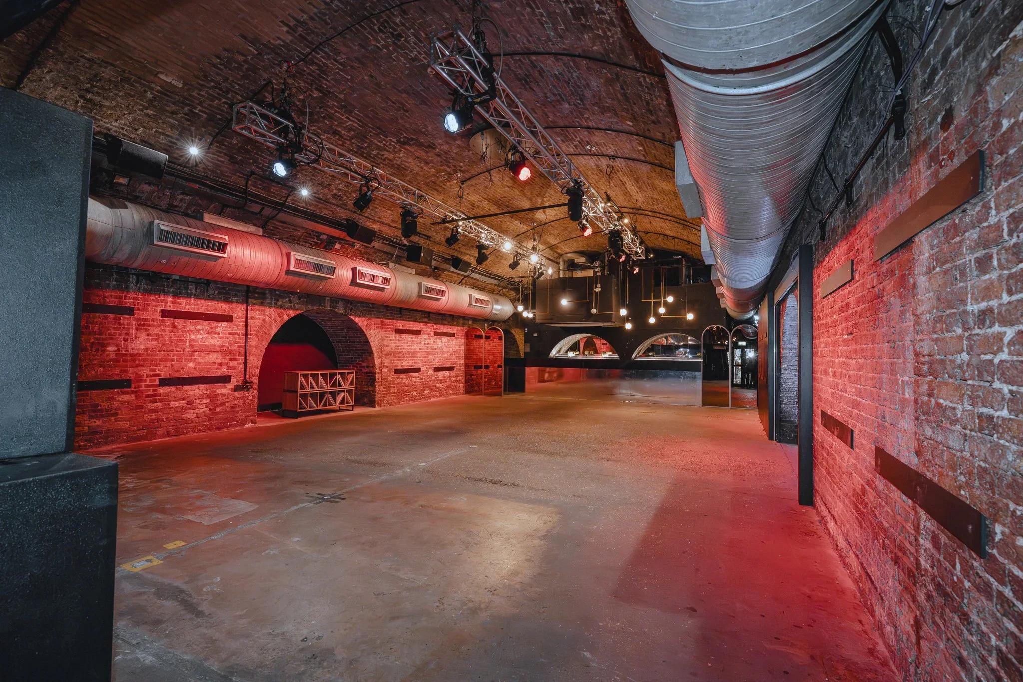 Railway arch with exposed ductwork and red uplighting at 83 Rivington Street