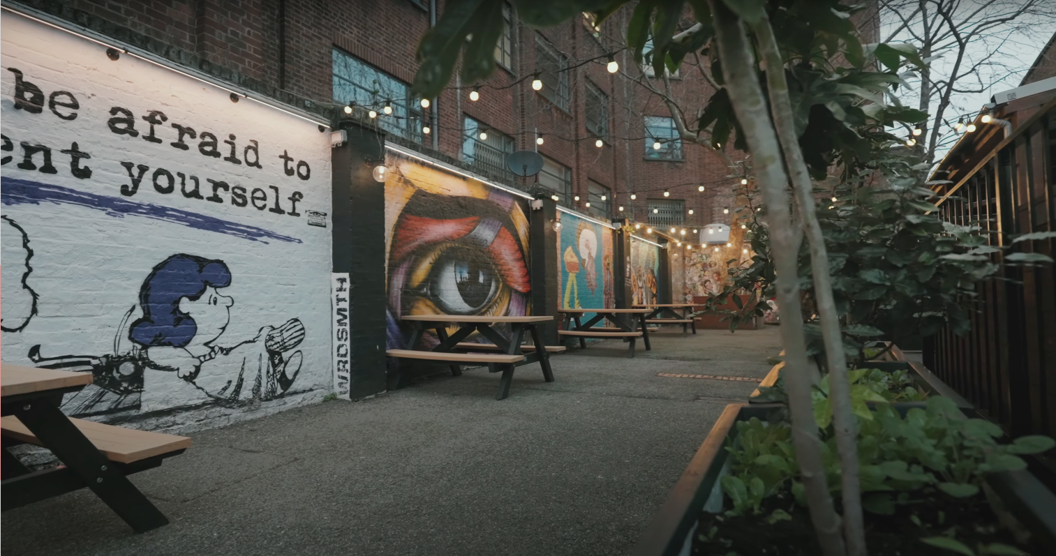 Outdoor courtyard with street-art murals and picnic benches, Shoreditch
