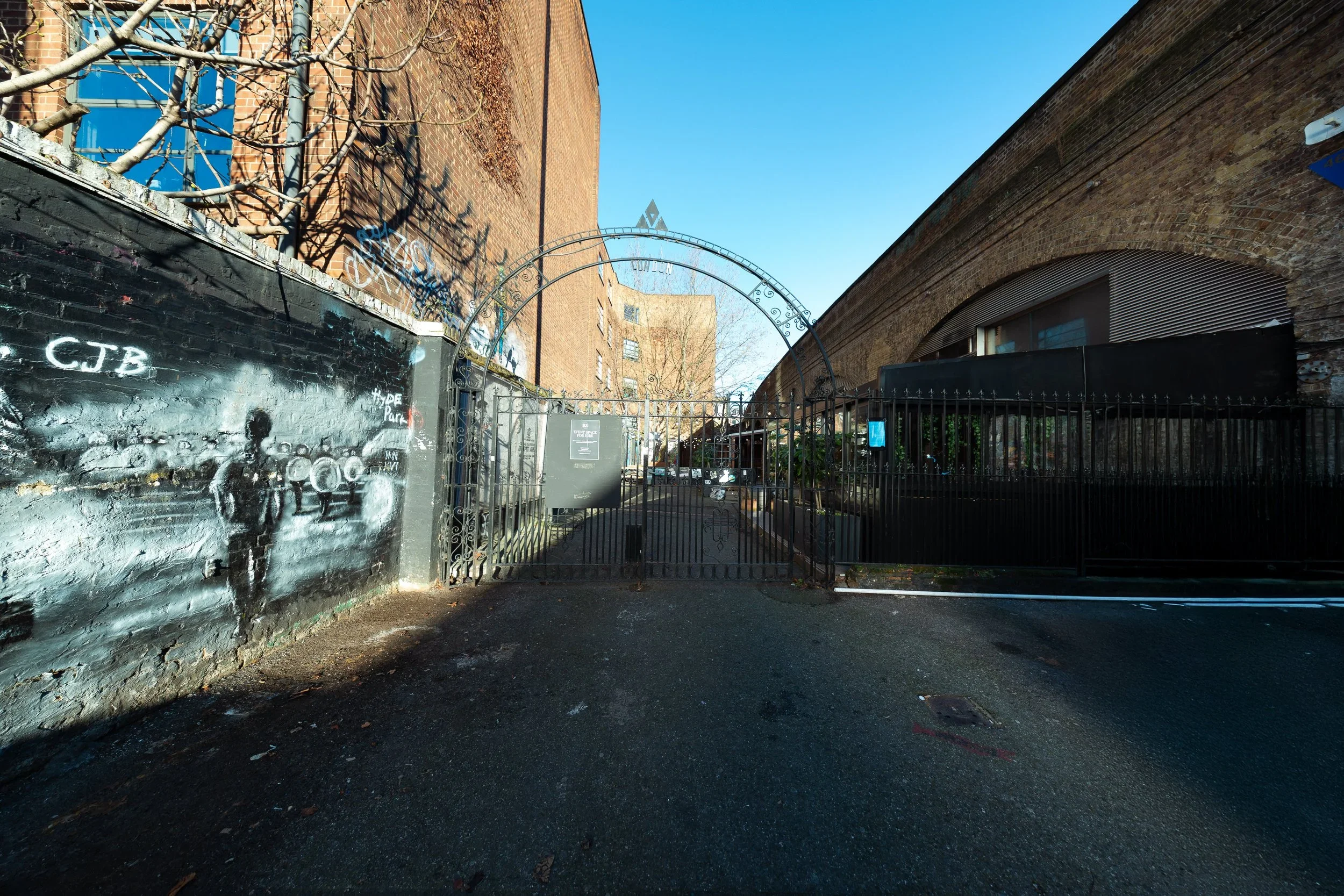 Courtyard gate and street-art lane beside the railway arches, Shoreditch