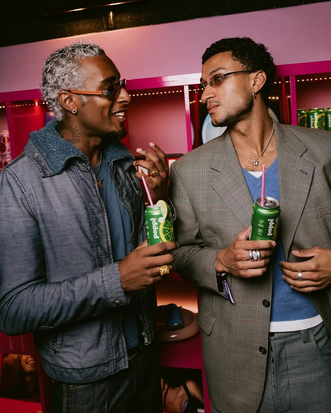 two men looking fashionable, enjoying Poppi drinks with a straw