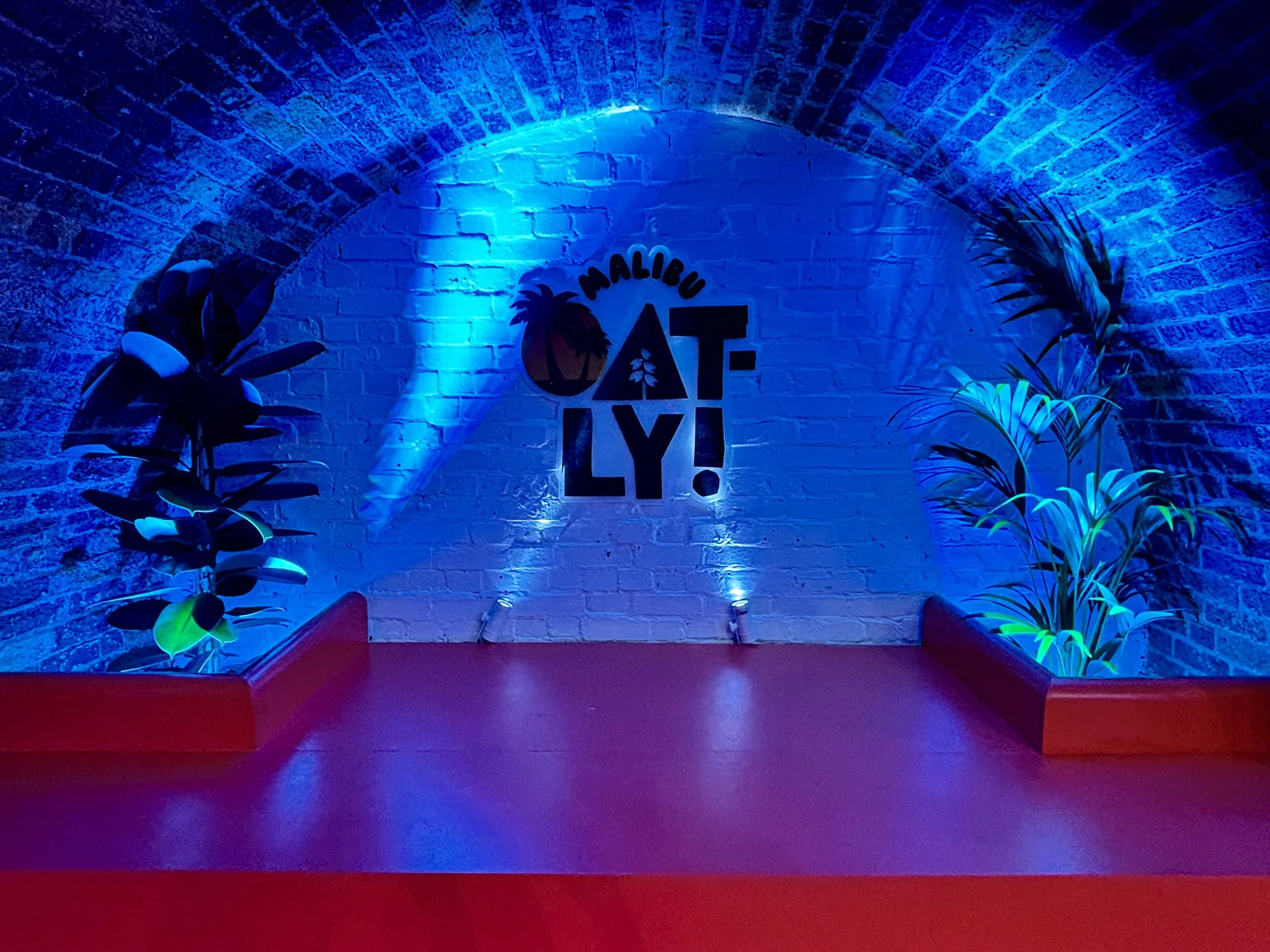Oatly brand activation stage with blue lighting under a railway arch