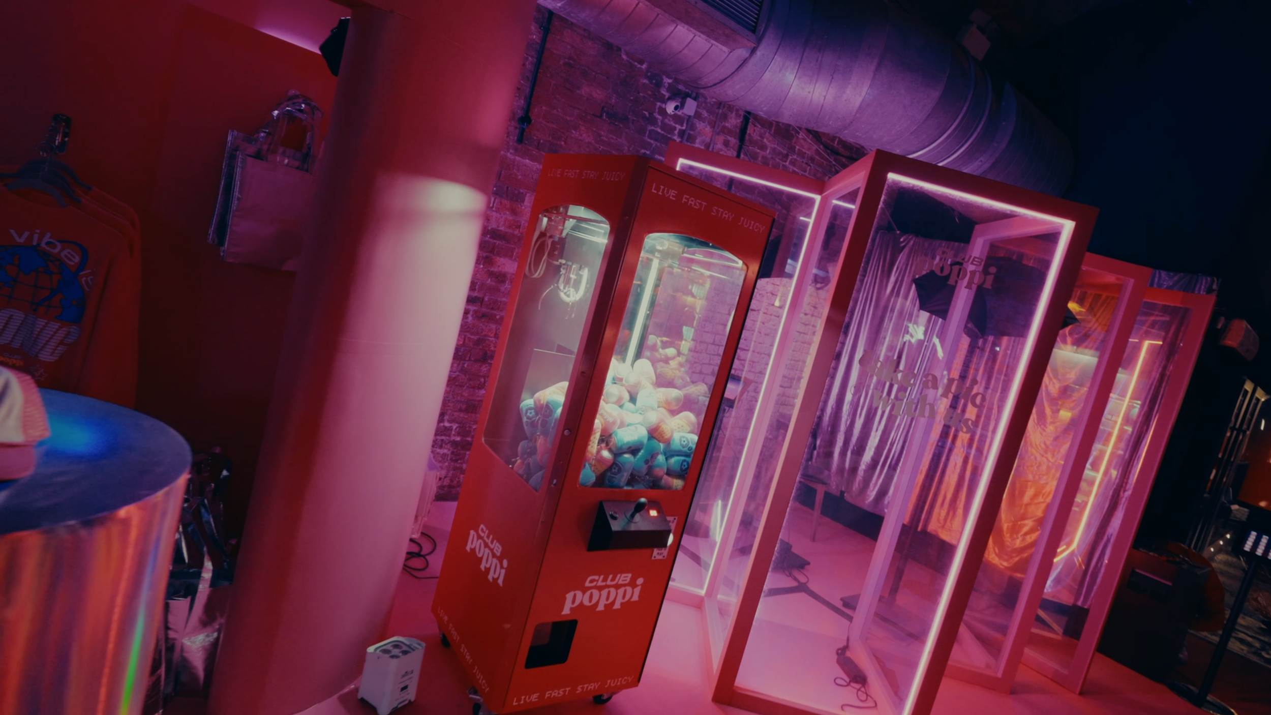 exposed brick wall with exhaust tubes industrial looking venue Pink vinyl wrap brand activation for Poppi drinks pink vinyl wrap soft toy dispenser silver curtain brand activation inspiration