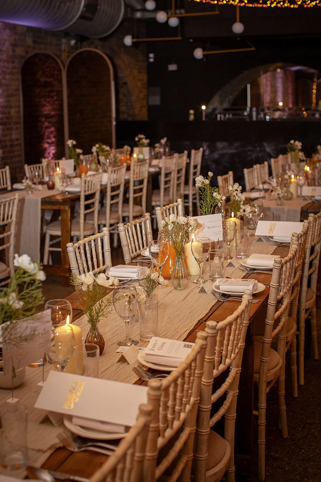 Wedding reception tables with candles and flowers in a railway arch