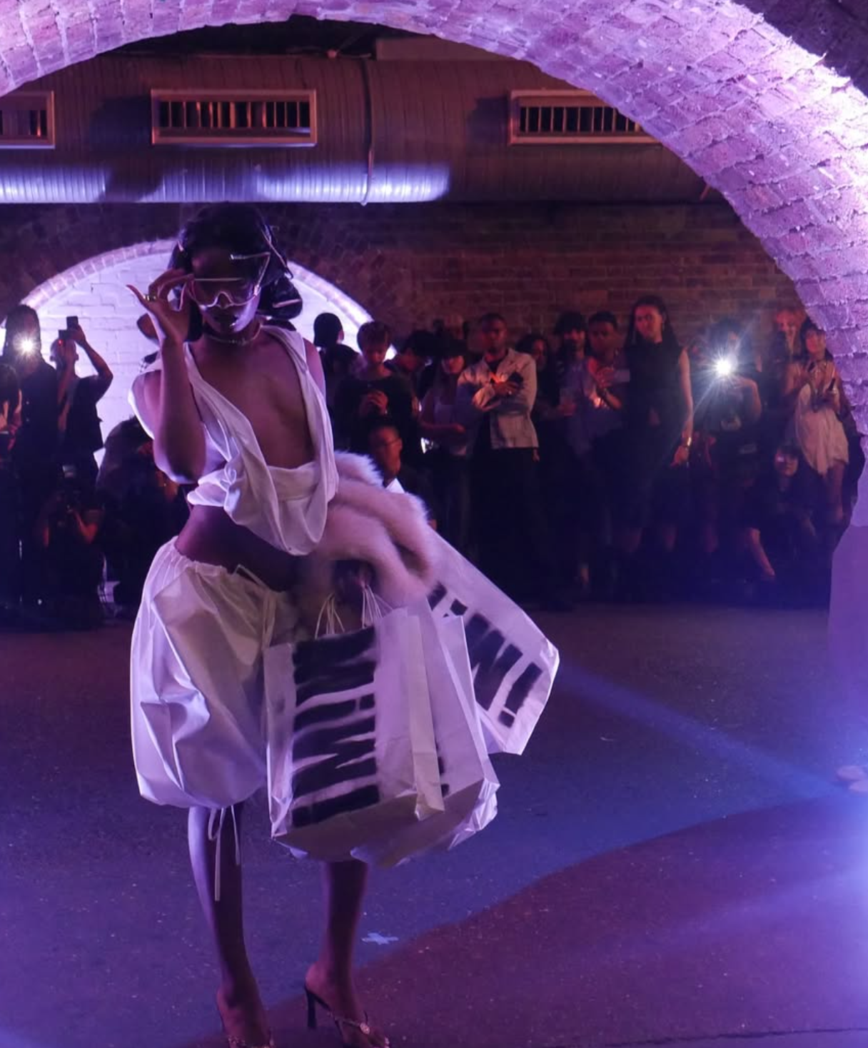 Model on the runway in a sculptural white outfit at a fashion show