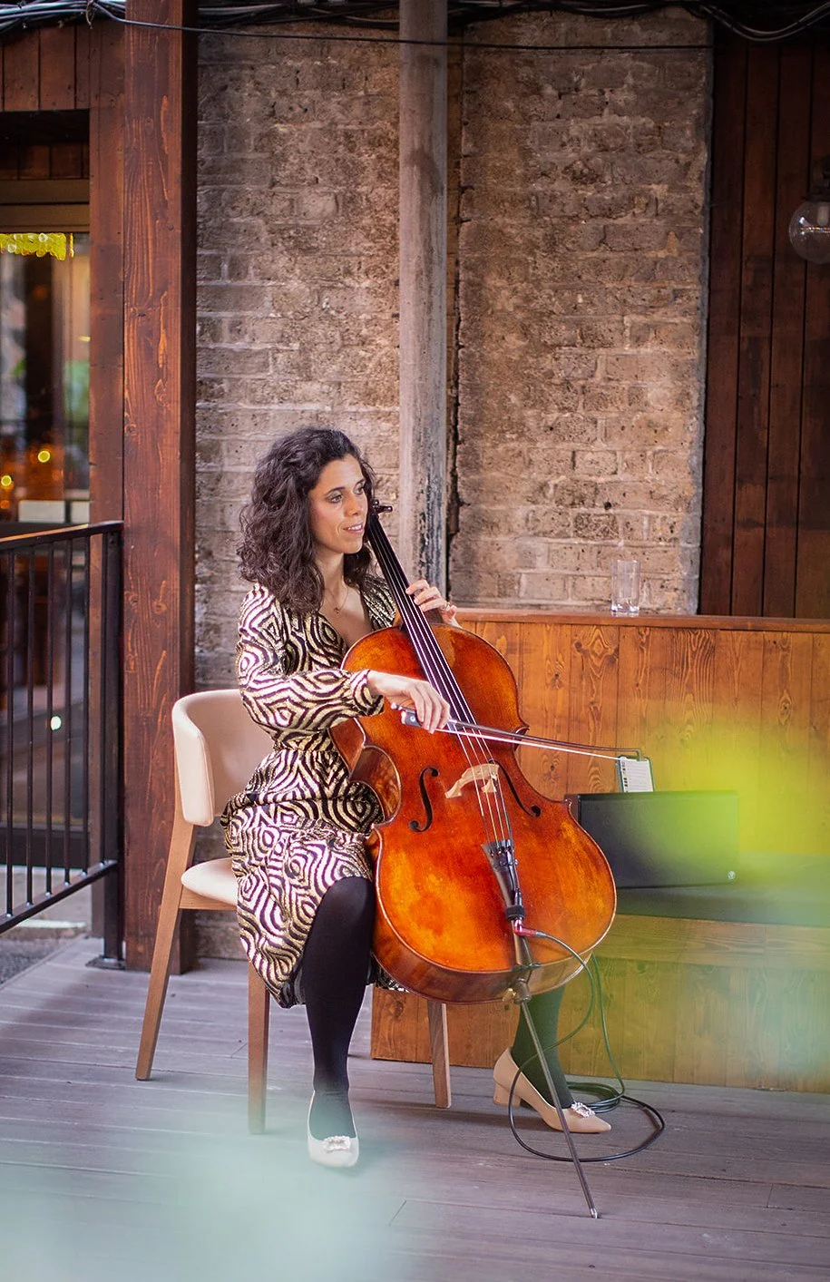 Cellist performing at a wedding reception with an exposed brick backdrop