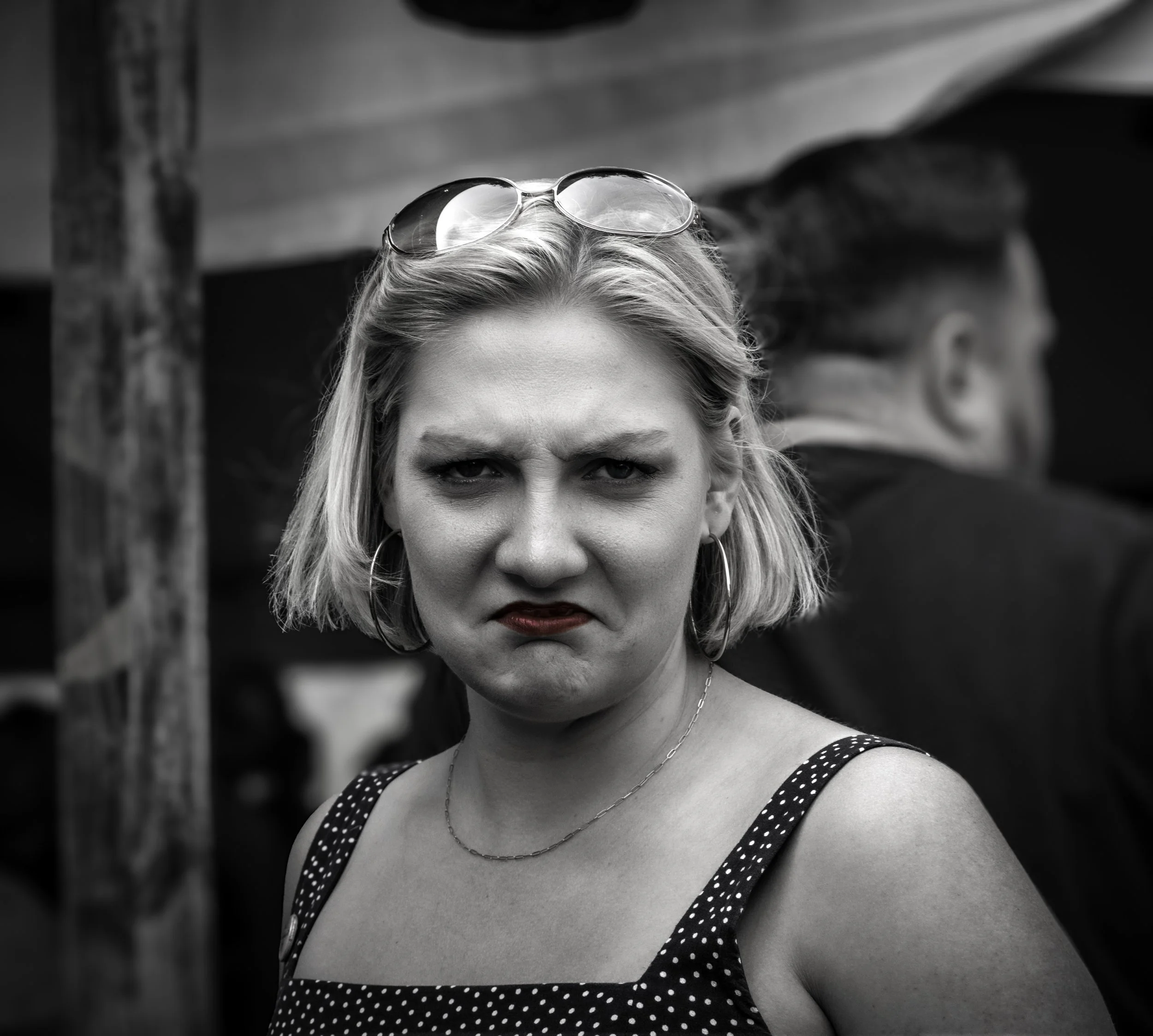 Not Impressed
Black and white close portrait of a woman with a skeptical expression at a crowded outdoor event. 