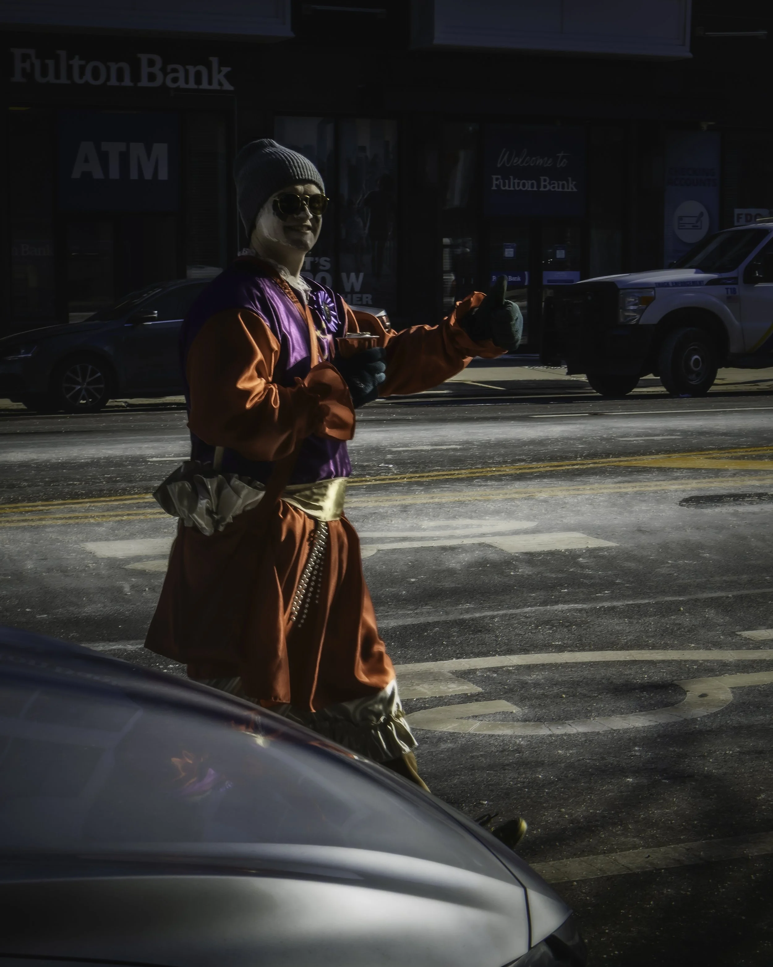 Street Showman
Parade participant in a bright satin costume gives a thumbs-up while walking through the street.