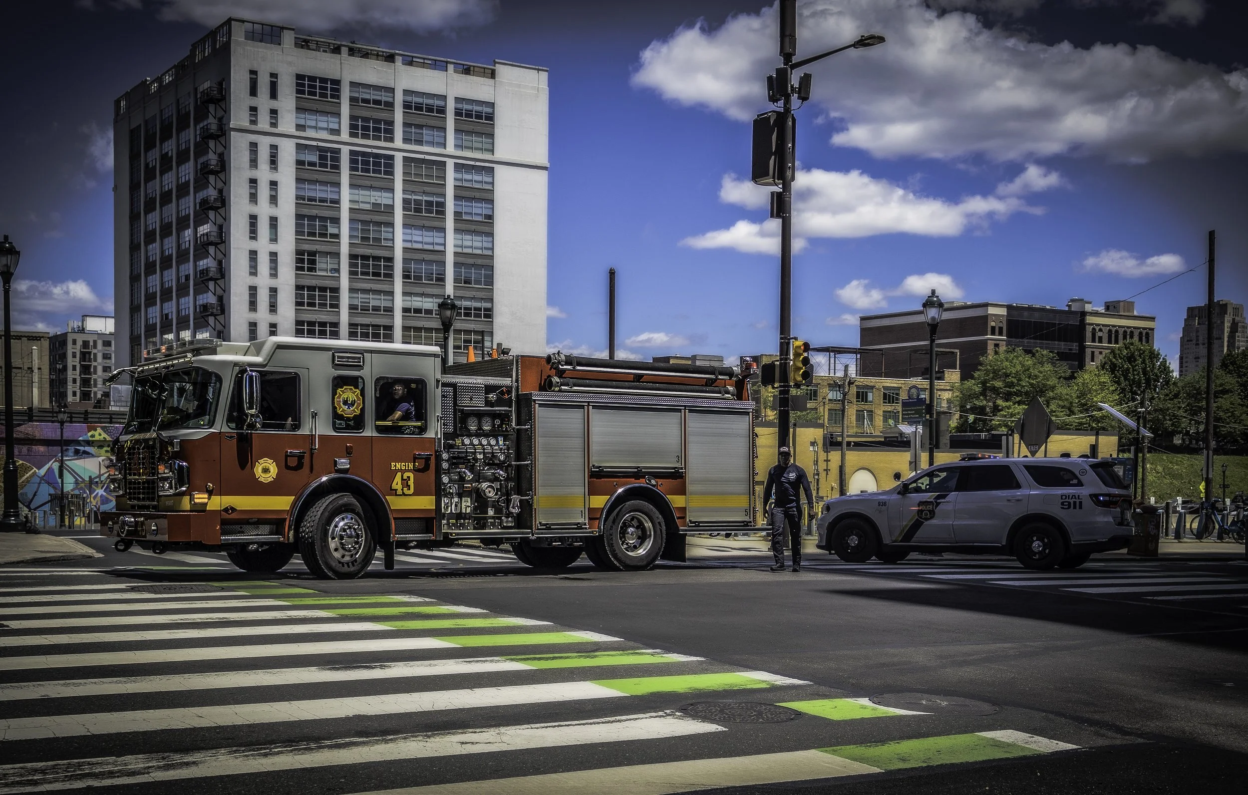 Guardians of the Intersection
Fire engine and police SUV pause beside a striped crosswalk while an officer stands between them.