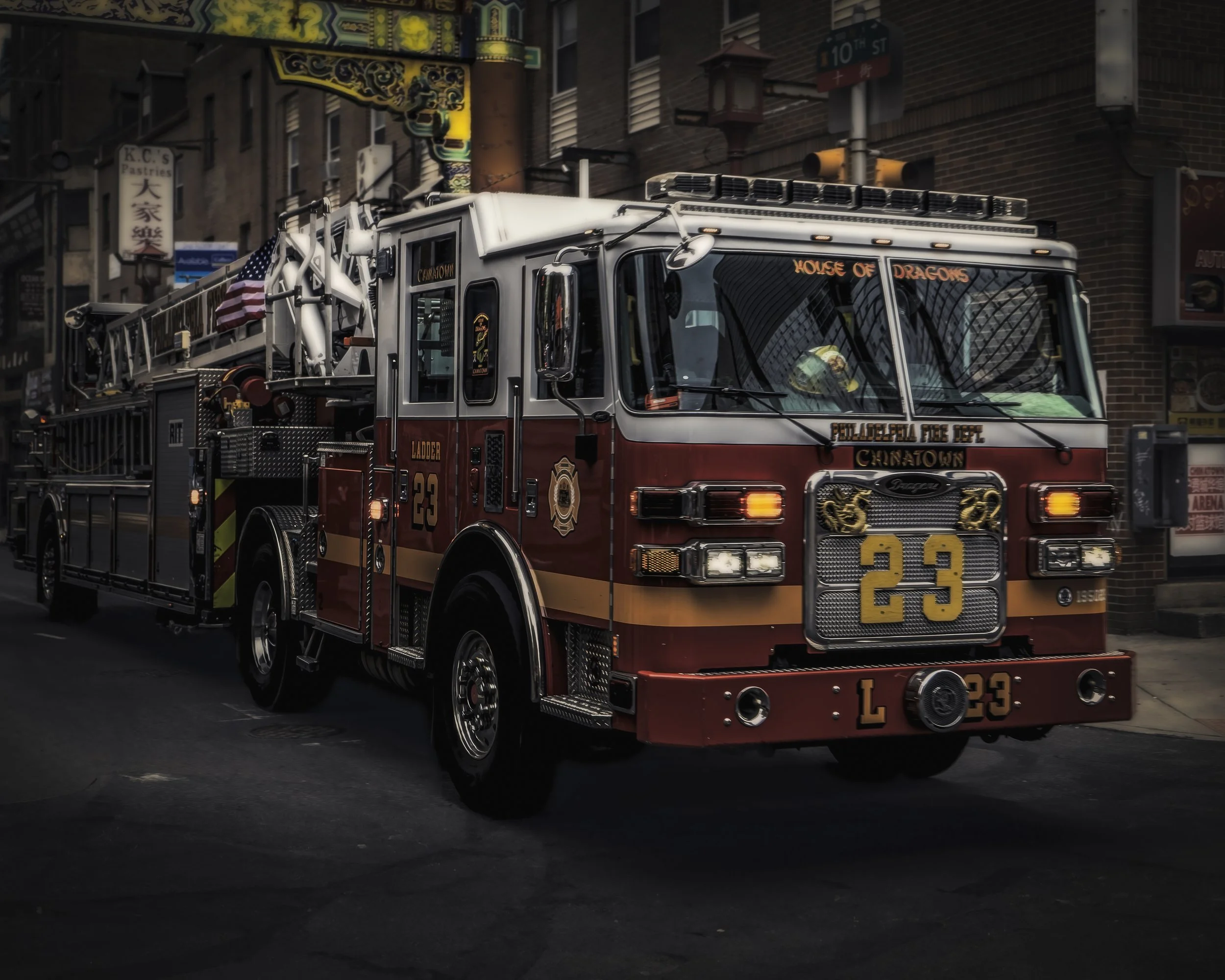 House of Dragons, Ladder 23
Fire ladder truck drives through a Chinatown street beneath an ornate gateway. 