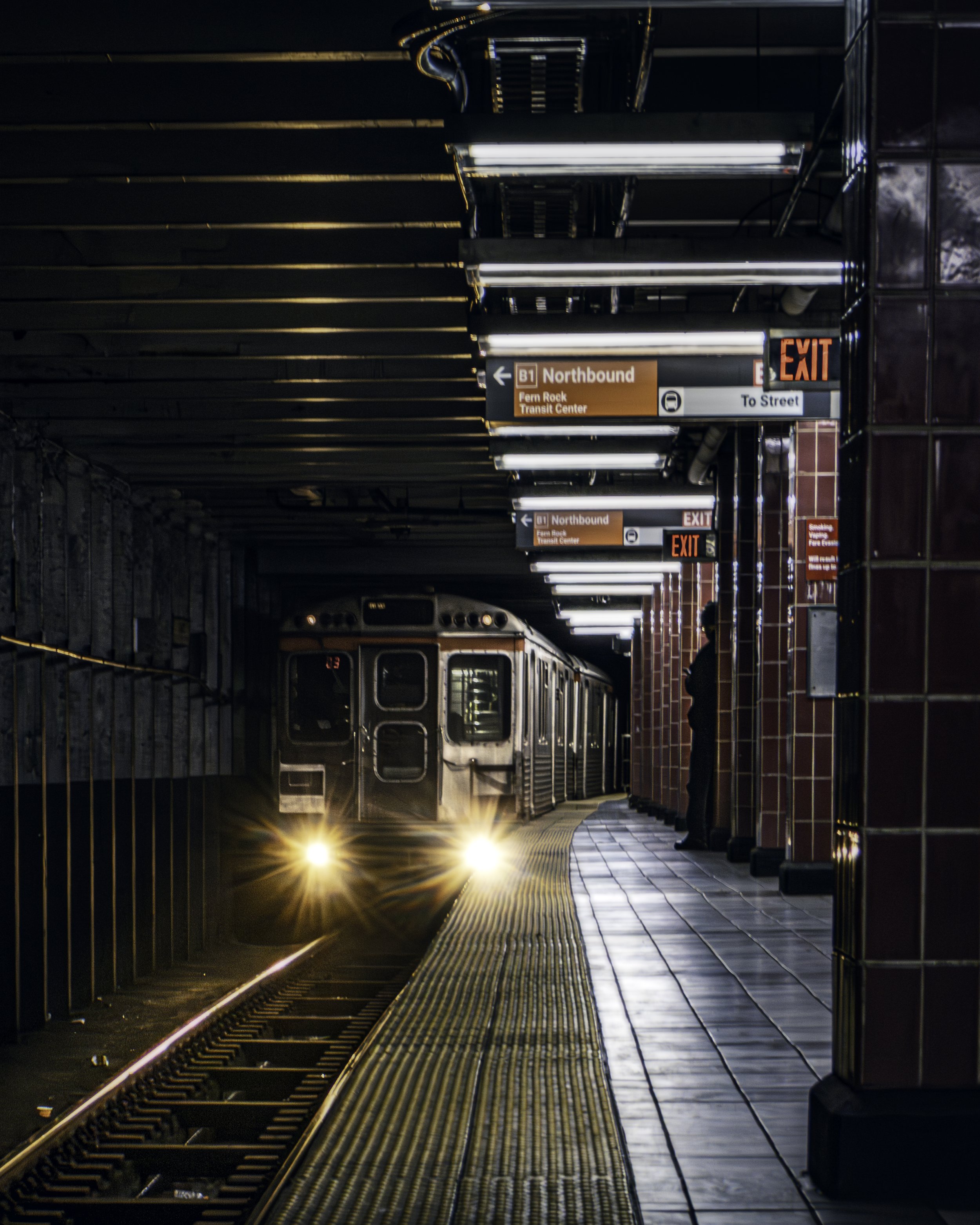 Platform Light
SEPTA at an underground station platform with a train arriving in the distance, yellow platform edge and receding overhead structure. Subway illuminated by fluorescent lights.