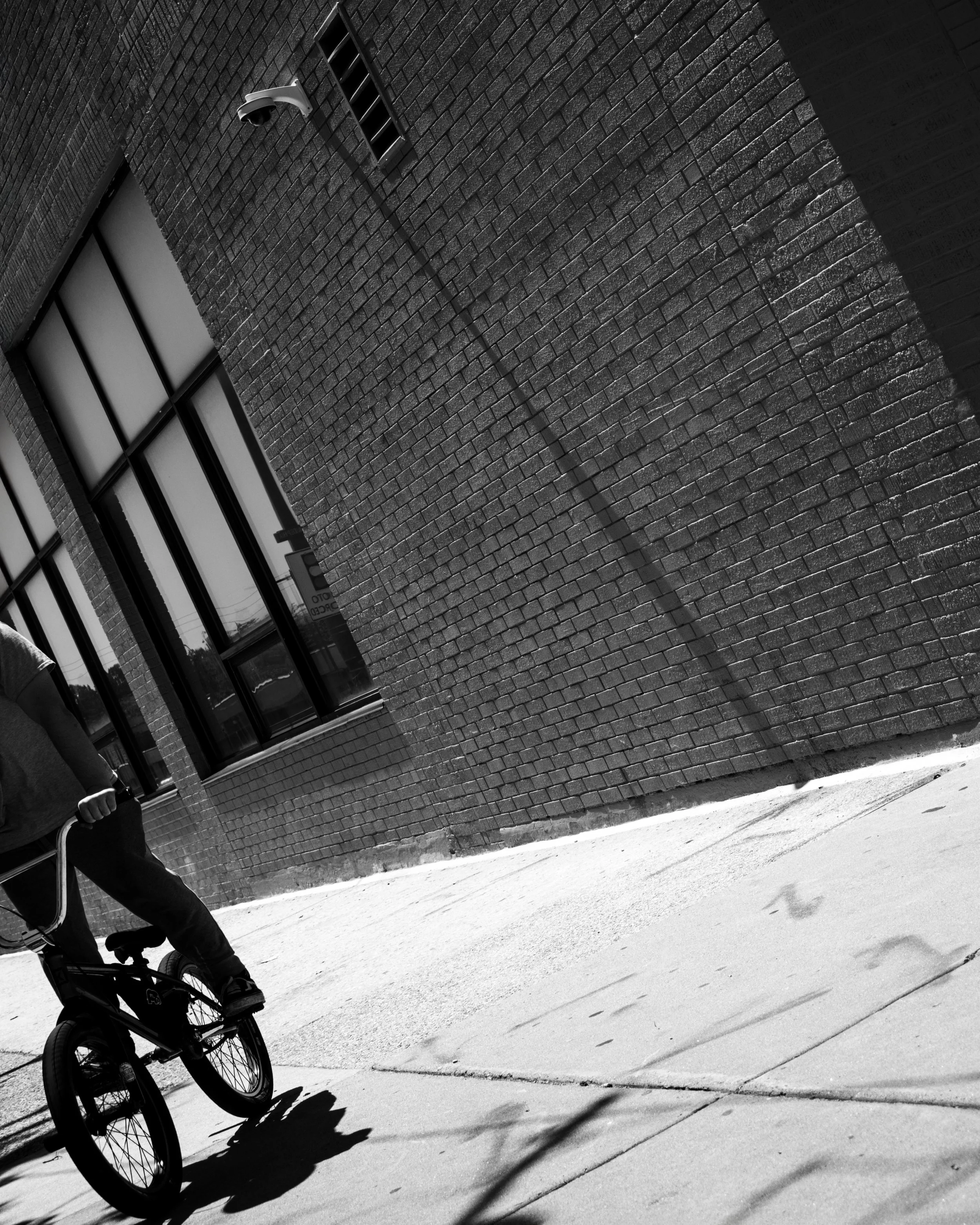 Edge of the Ride
Tilted black and white street photograph near Broad Street and Oregon Avenue, with a BMX rider partially entering the frame beside a long brick wall.