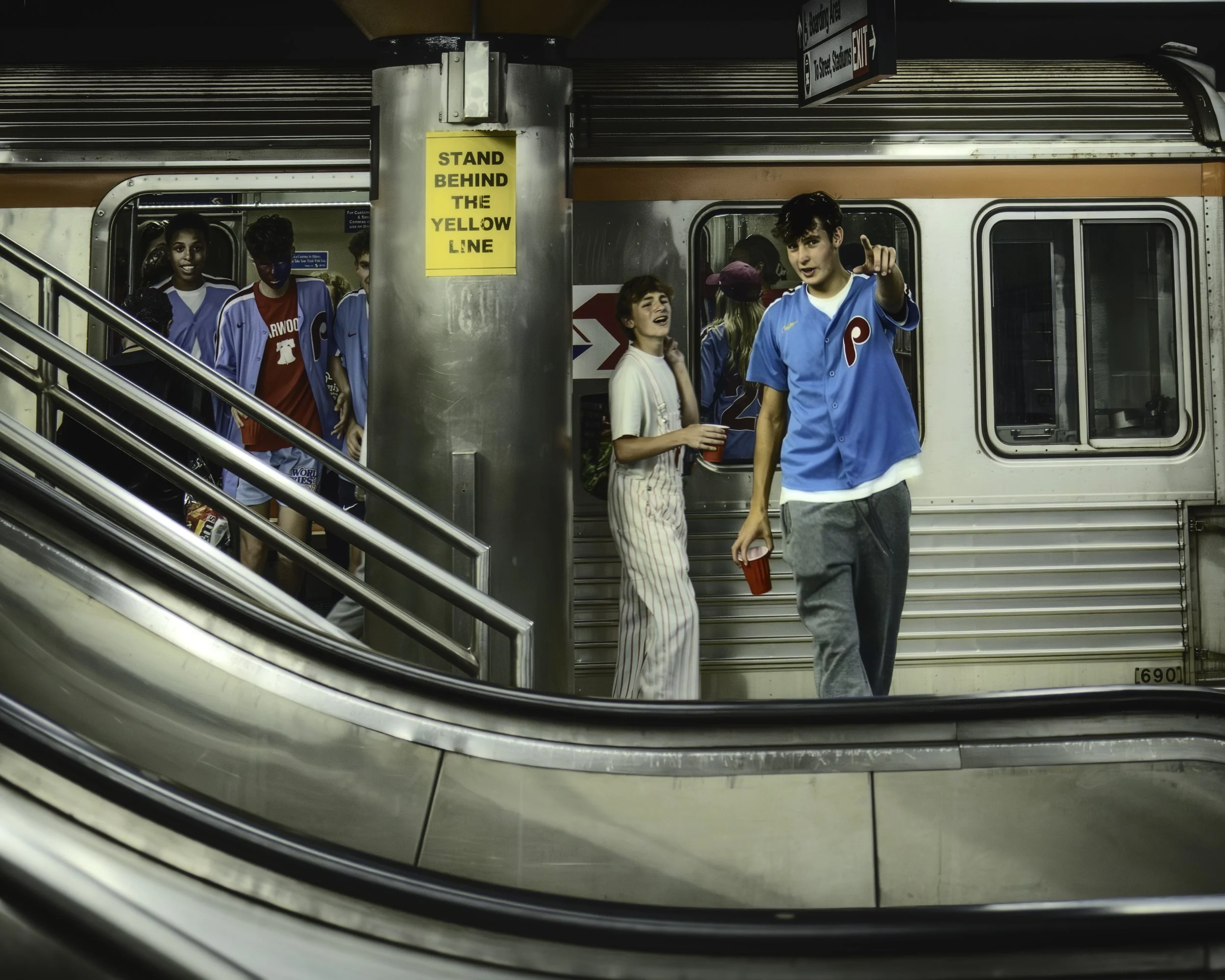 Youthful Game Day Expression
Group of young baseball fans steps off a subway train as one points toward the camera. 