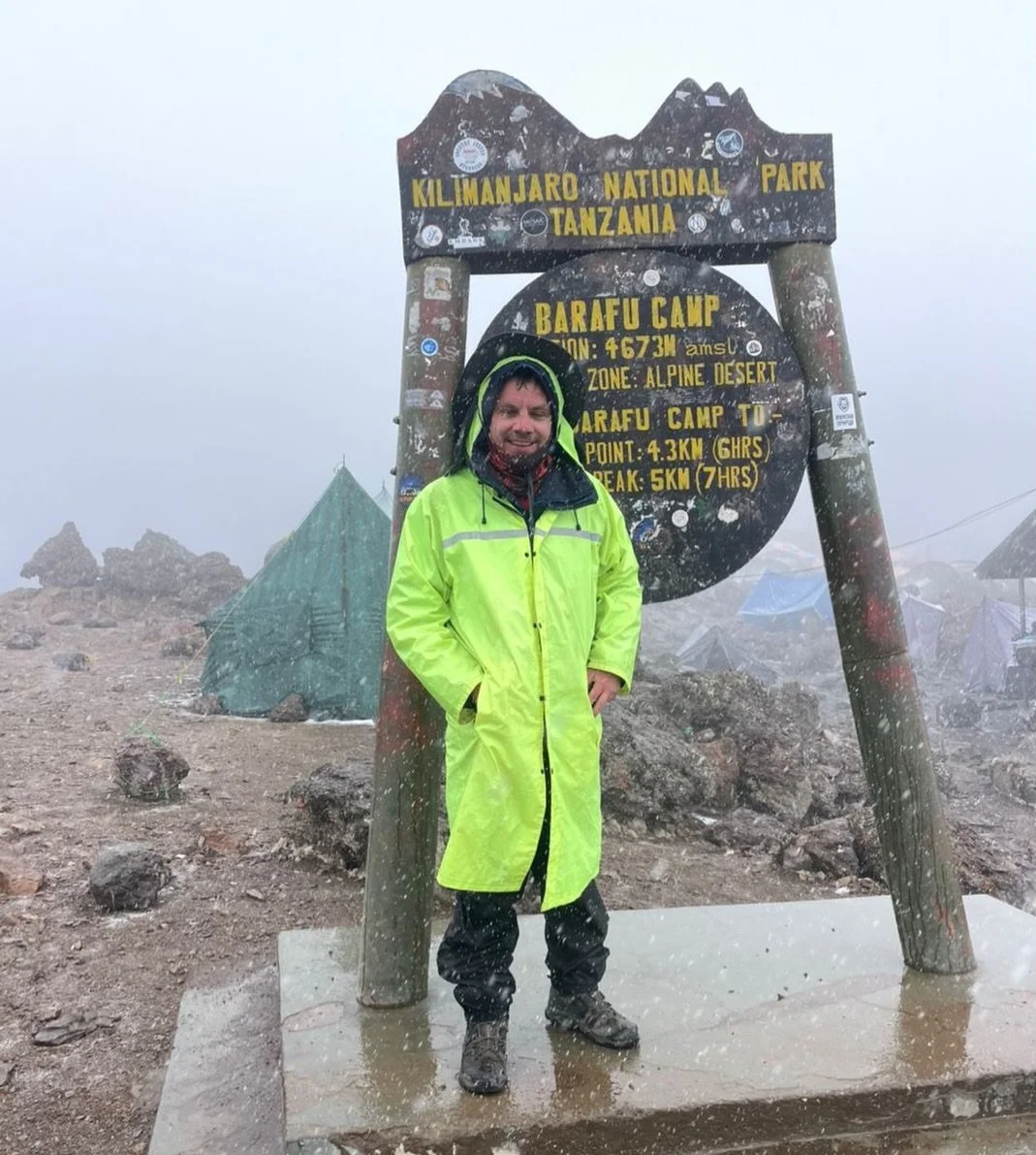 Ed stands at Barafu Camp &ndash; 4,673m.
On the slopes of Mount Kilimanjaro.

No filters.
No postcard skies.
No comfort.

Just cold.
Wind.
Sleet cutting through every layer.

This is the reality before the summit push.

People see the Uhuru Peak phot