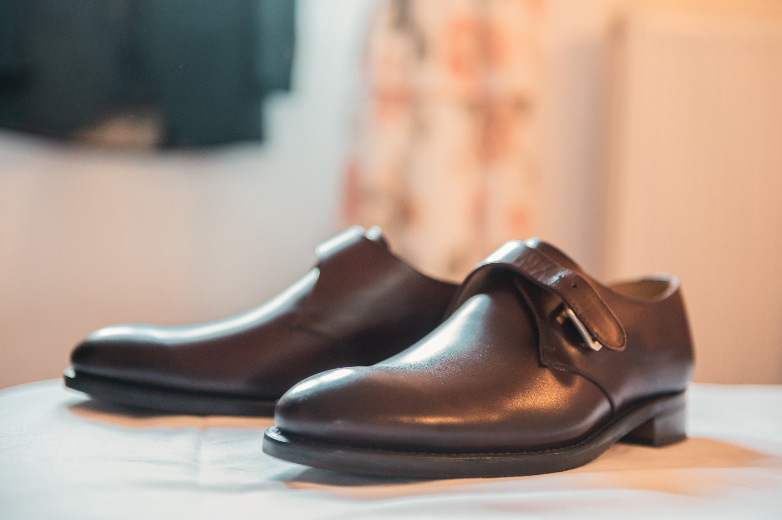 Une paire de chaussures en cuir marron brillant posée sur une surface blanche avec un fond flou