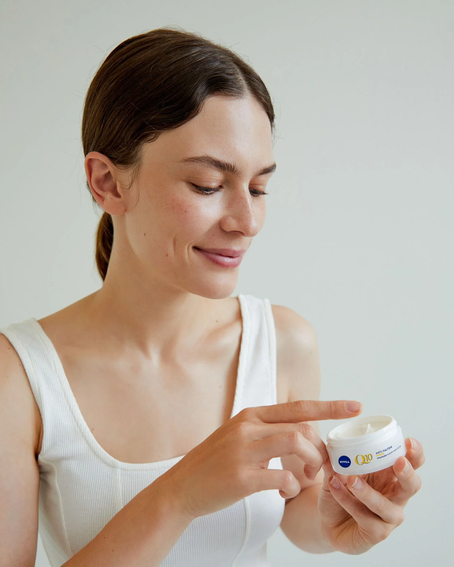 Woman opening a jar of Nivea Q10 anti-wrinkle face cream