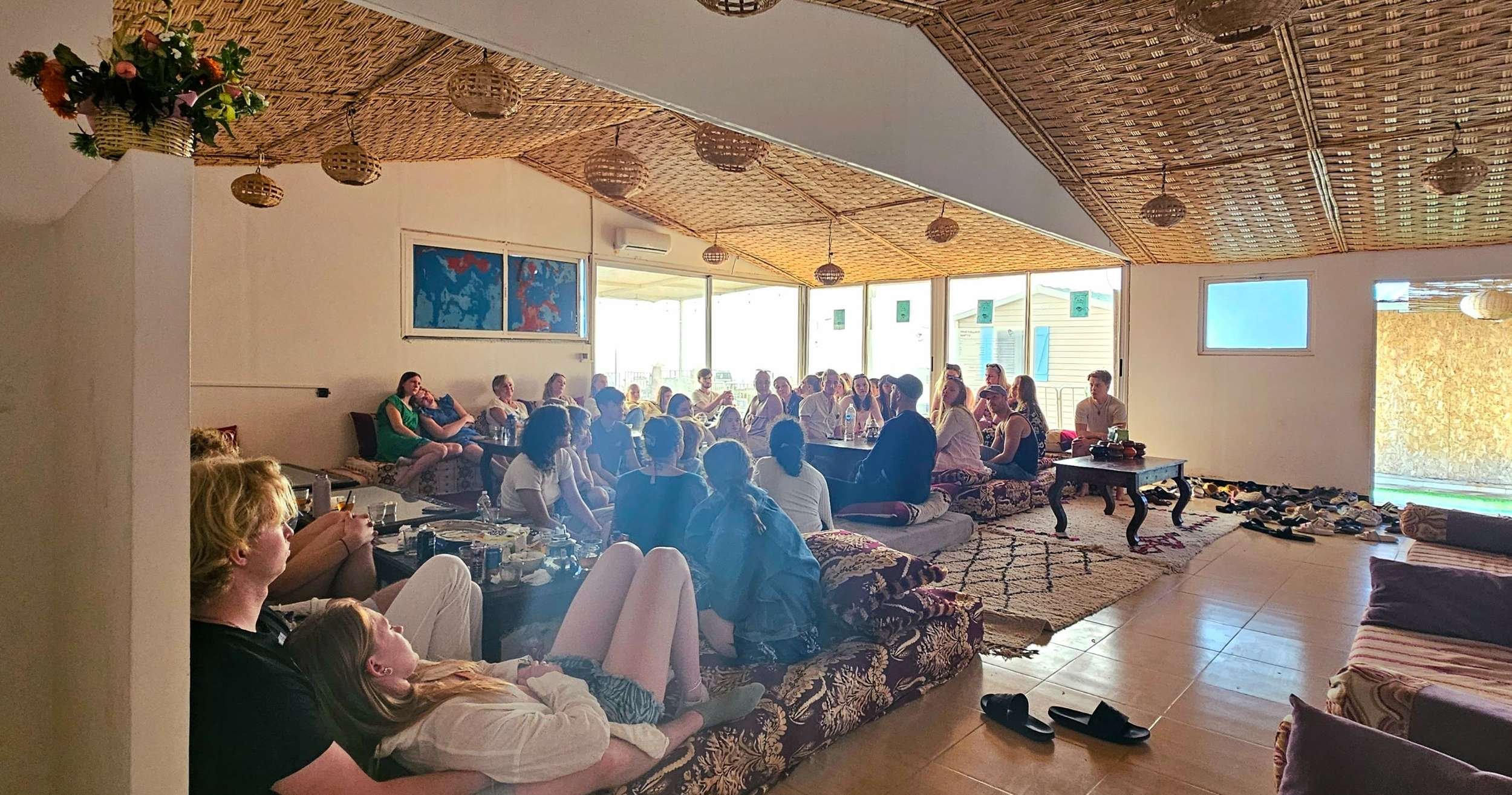 Familier og grupper samles på ChilloutLounge for en avslappet atmosfære, hvor man deler måltider, historier og opplevelser etter en dag med aktiviteter og surfing.